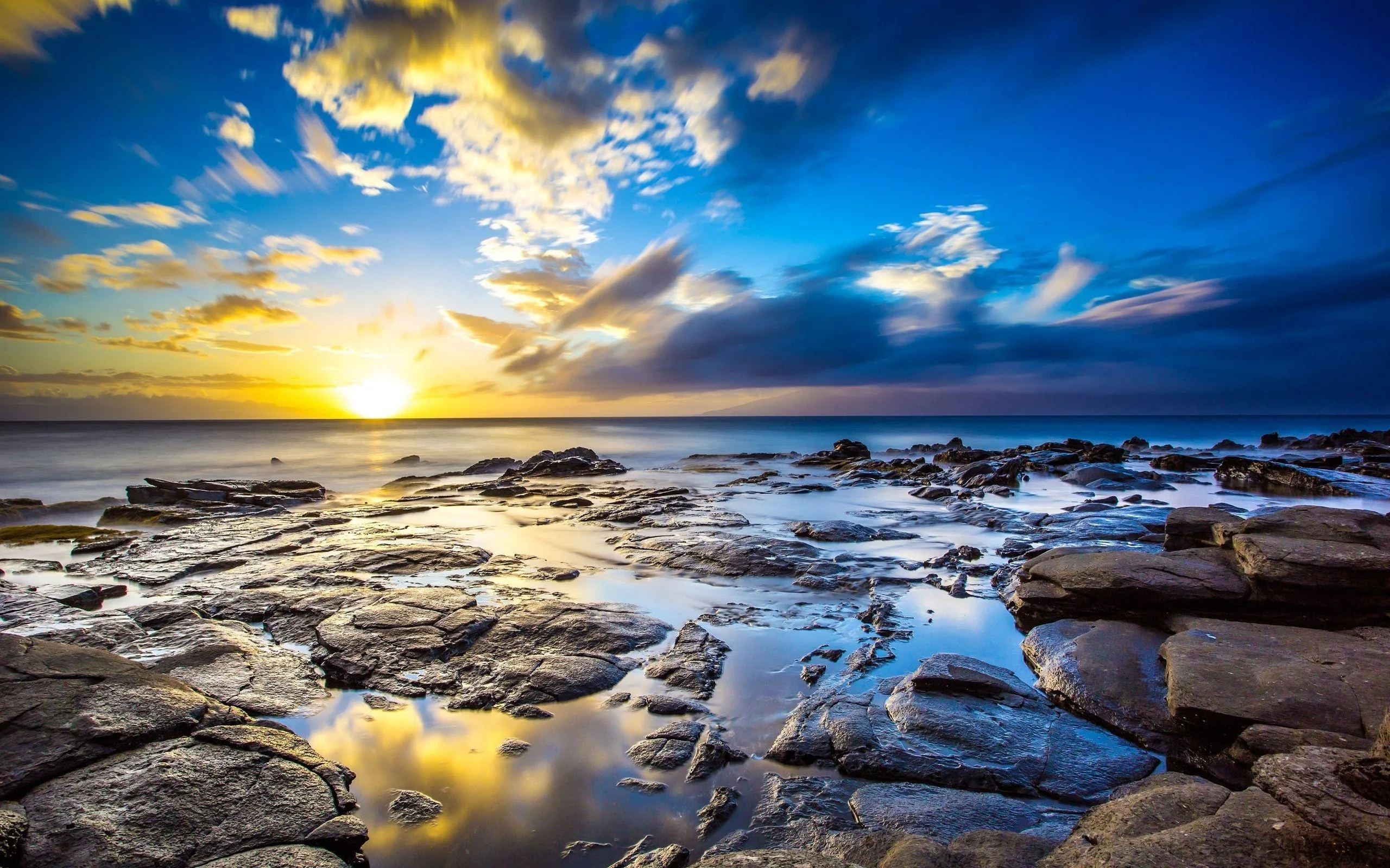 Sunrise over Smooth Rocks on Shore Under a Dramatic Sky