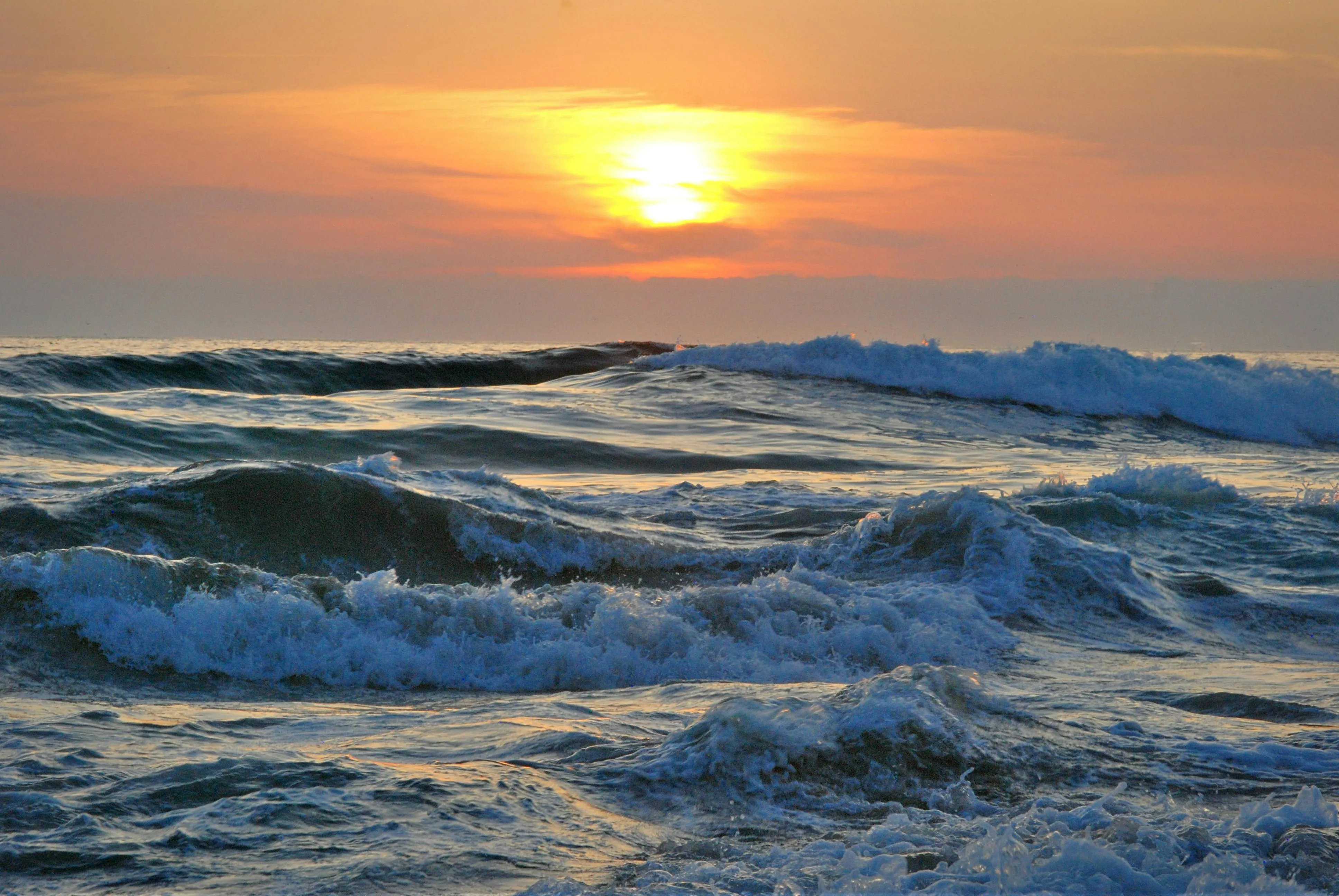 Sunset over Ocean Waves with Warm Orange Sky Wallpaper