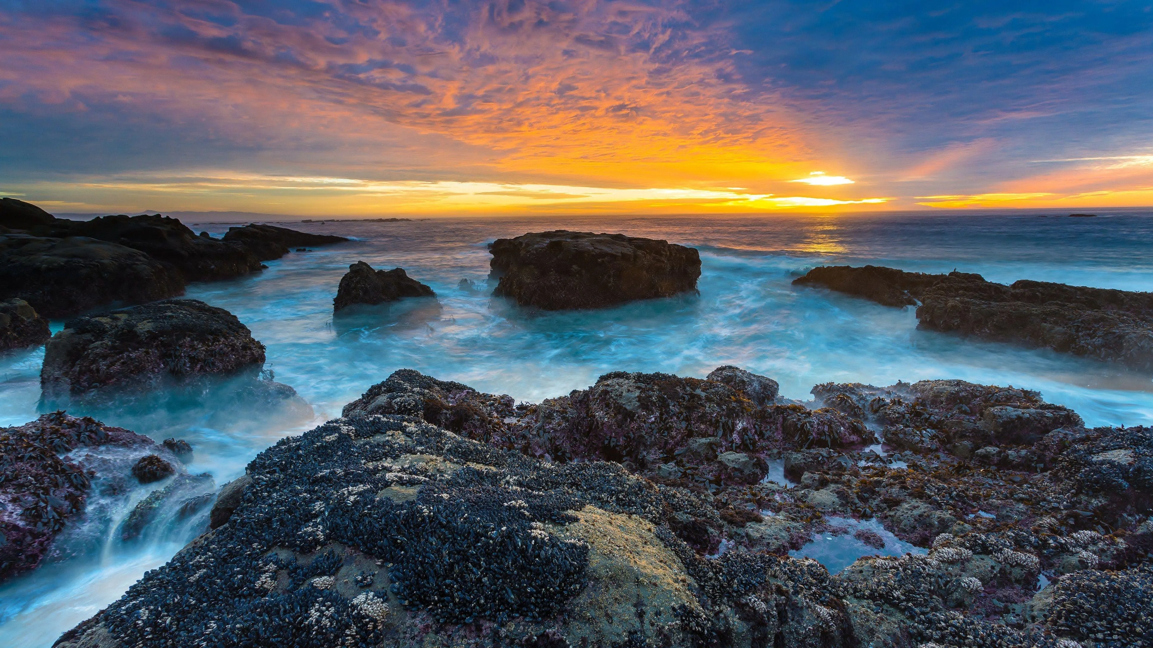 Sunset over a Rocky Beach with an Orange and Purple Sky