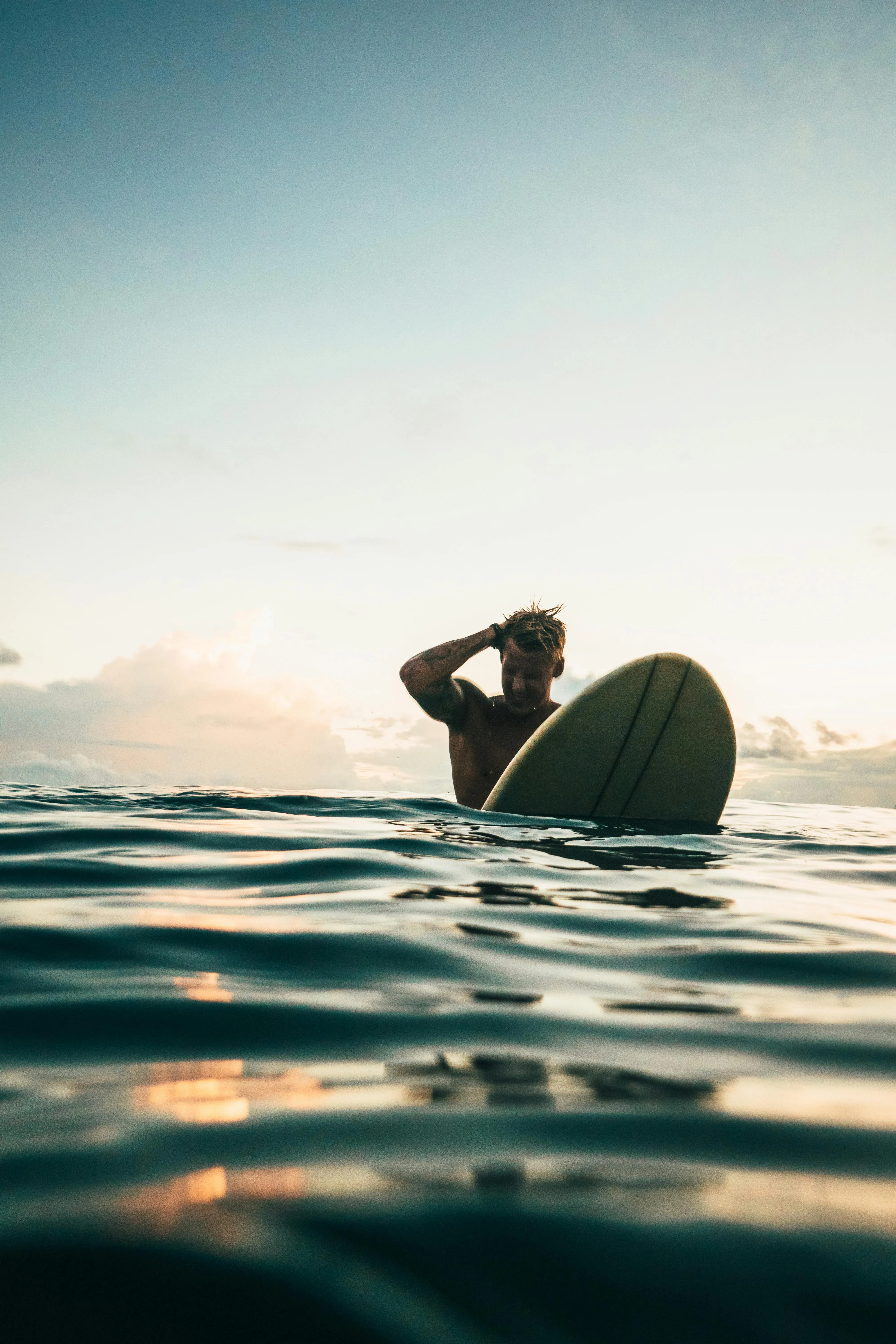 Surfer Paddling in Calm Ocean Water During a Golden Sunset
