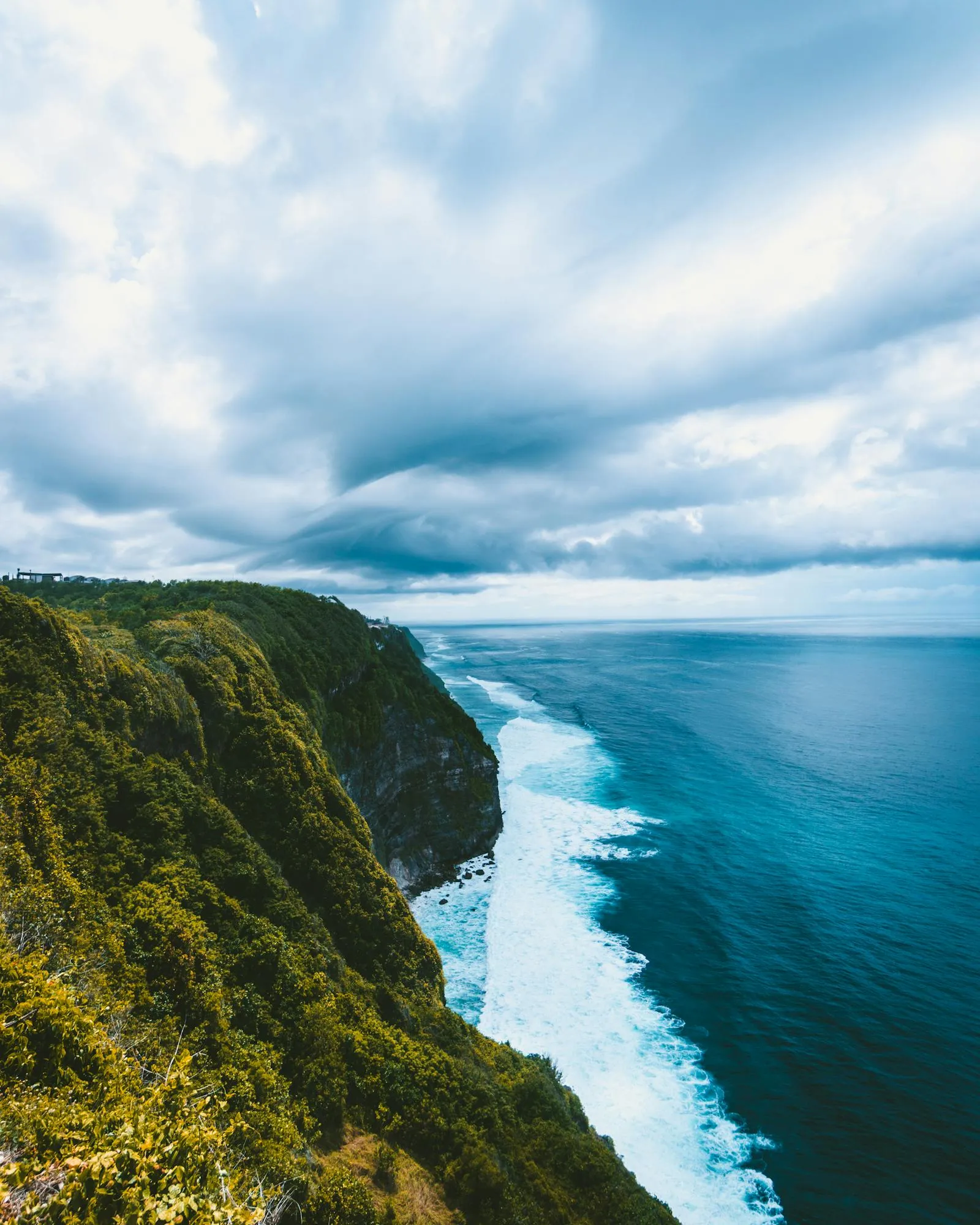 Tall Green Mountain with Waves Crashing and a Cloudy Sky