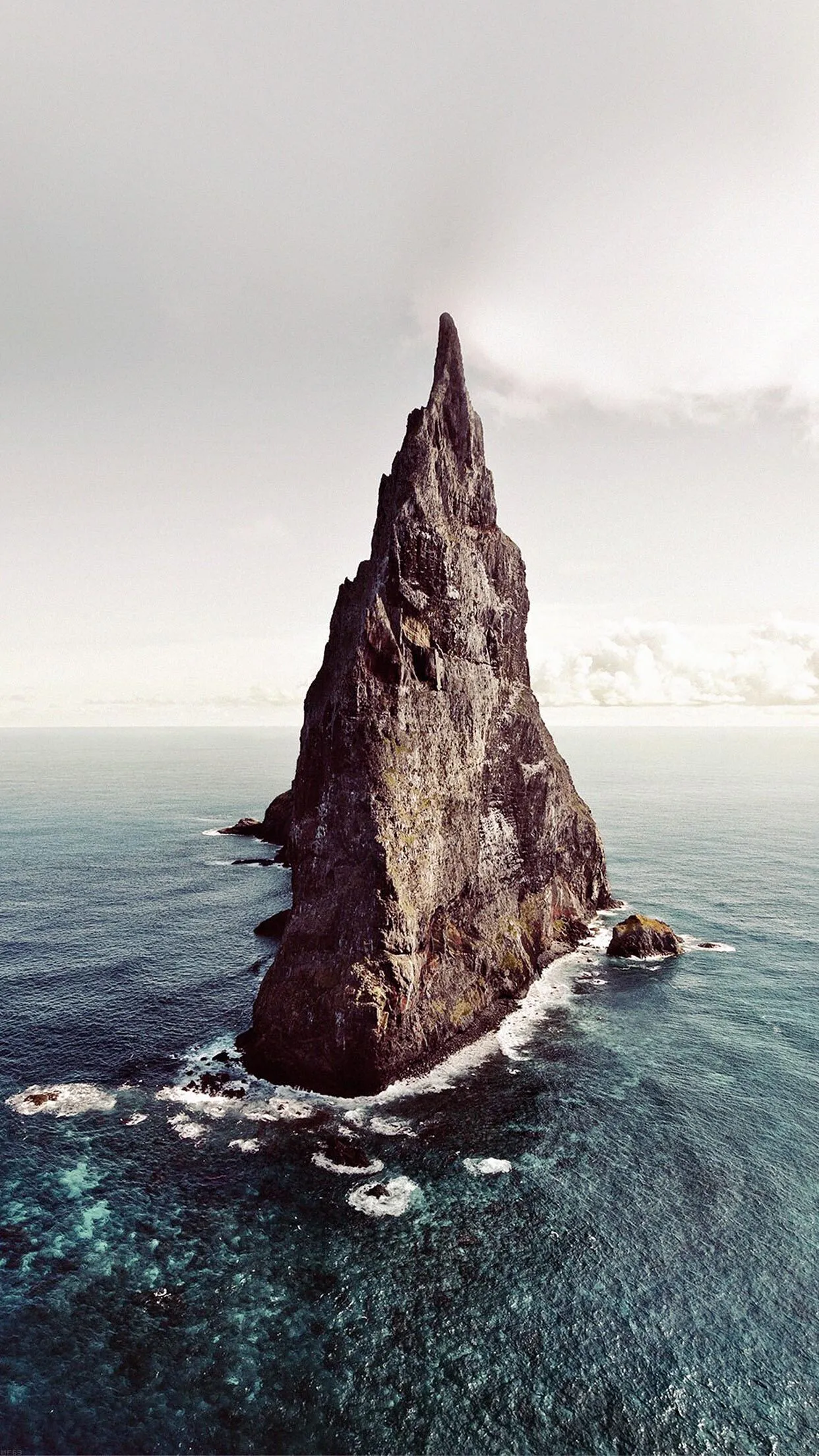Tall Pointed Rock Formation Rising from the Ocean Waves