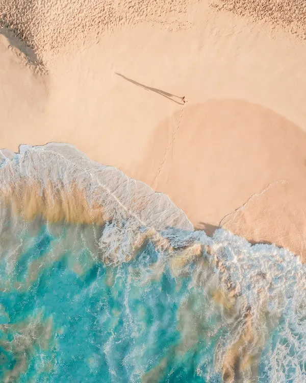 Top View of Clear Waves Crashing on a Sandy Beach Wallpaper