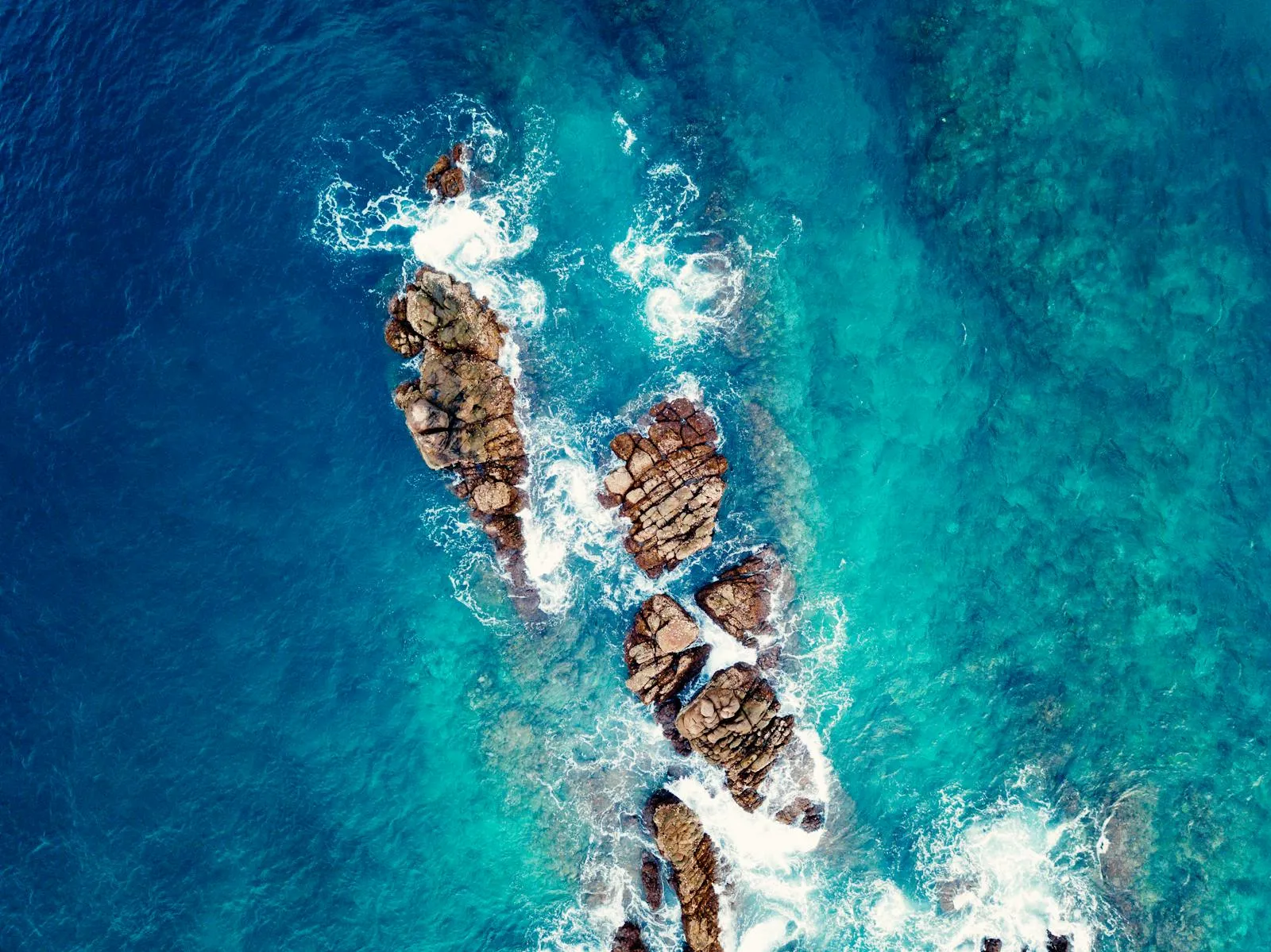 Top View of Crashing Waves over Jagged Coastal Rocks
