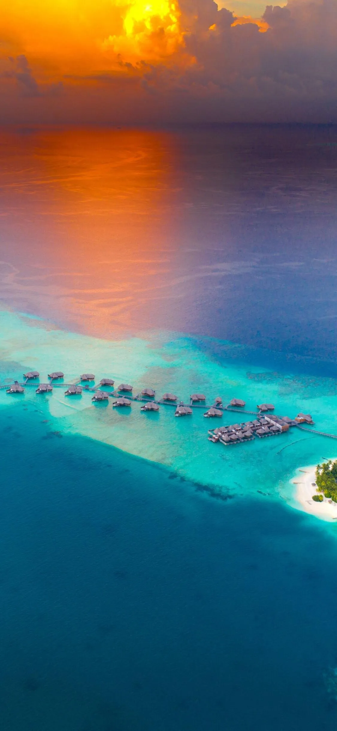 Top View of Overwater Bungalows Reflecting Orange Sunset