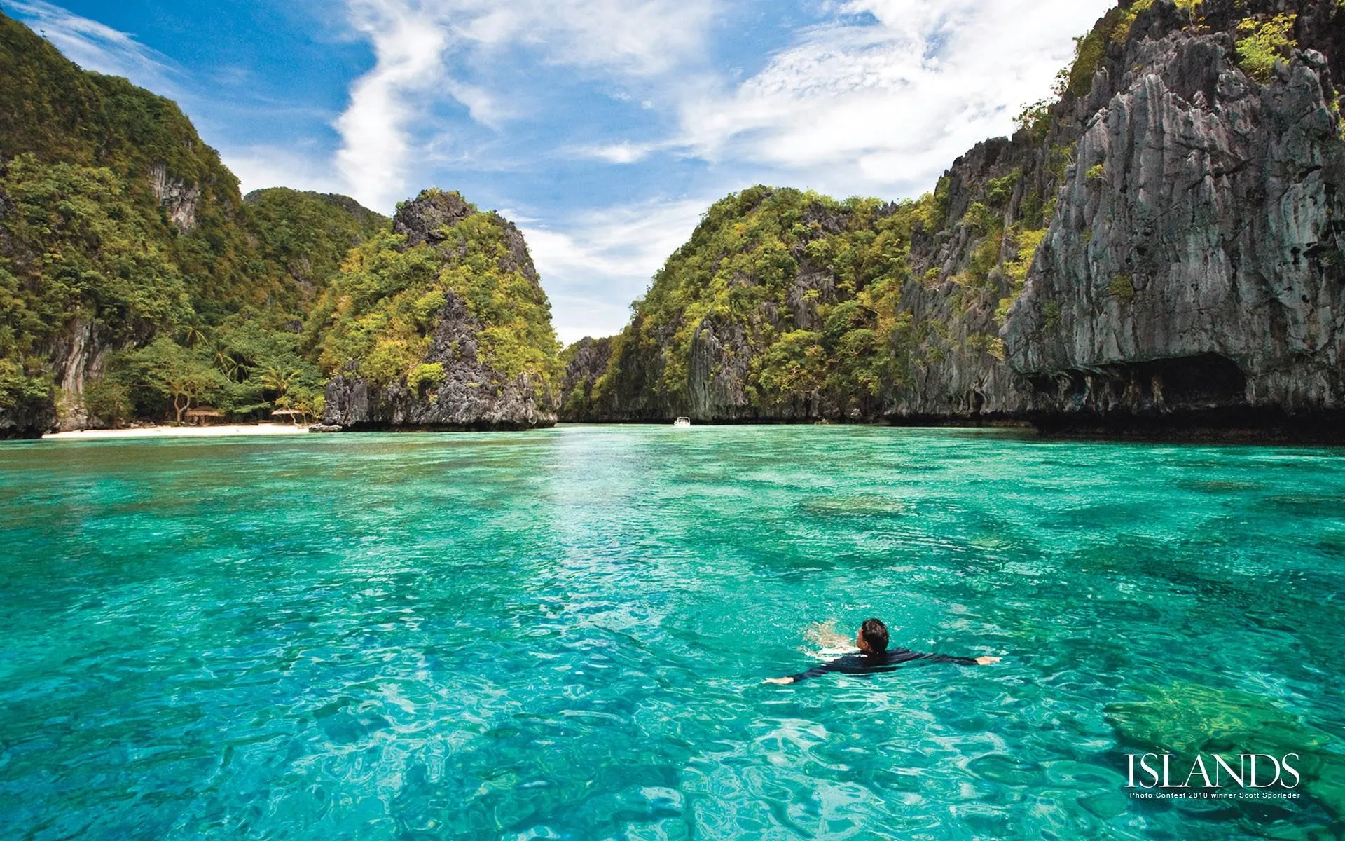 Turquoise Water by Tall Cliffs with a Swimmer Free Wallpaper