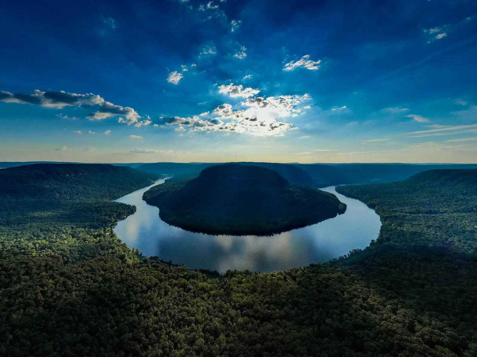 U Shaped Lake Water with Dense Forest Under a Dramatic Sky