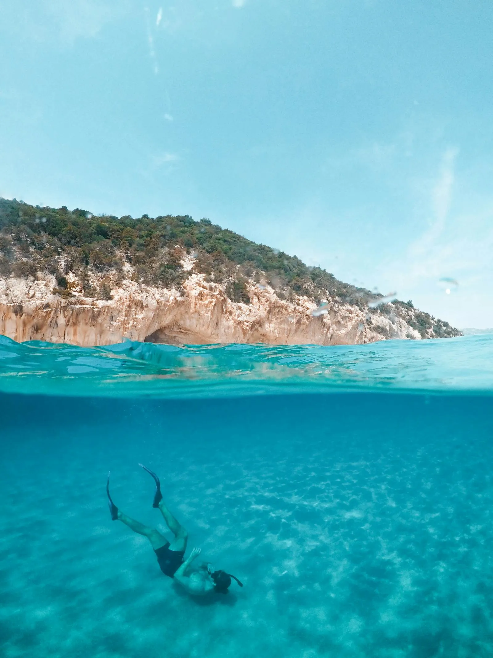 Underwater View of a Man Swimming Near a Rocky Coastline