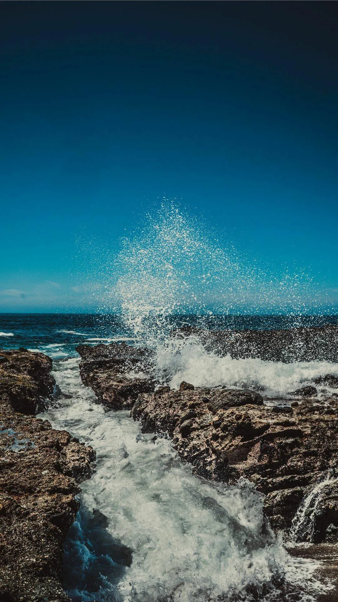 Waves Crashing on a Rocky Coastline with Deep Blue Water
