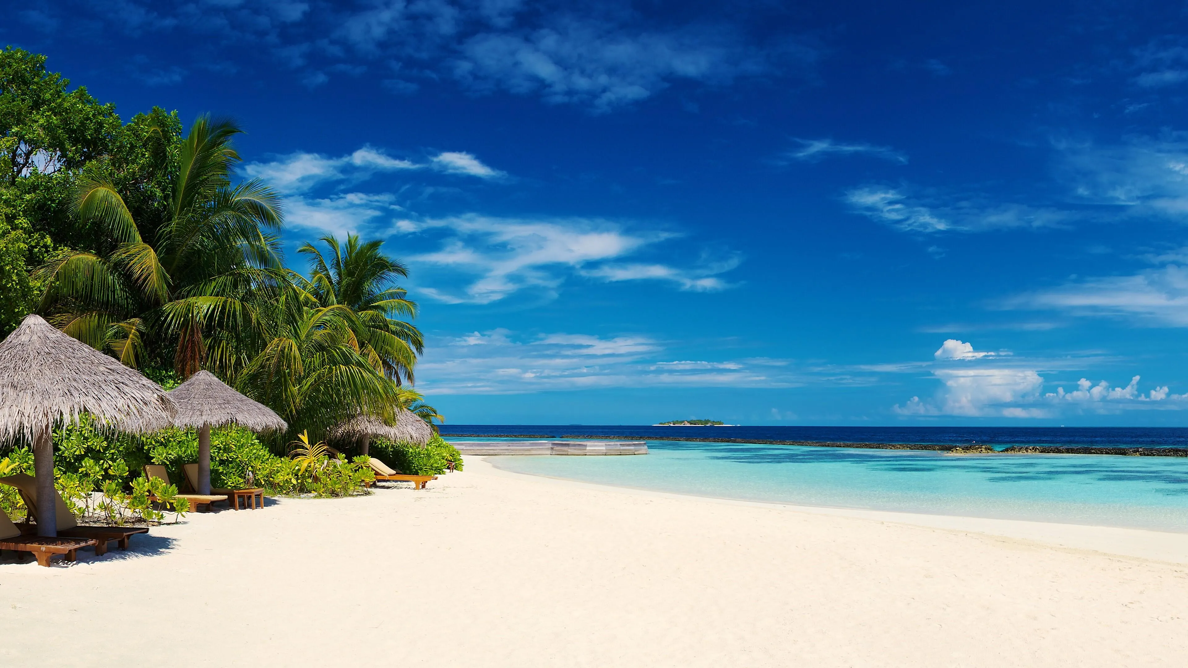 White Sandy Beach with Huts Under Clear Blue Sky Wallpaper
