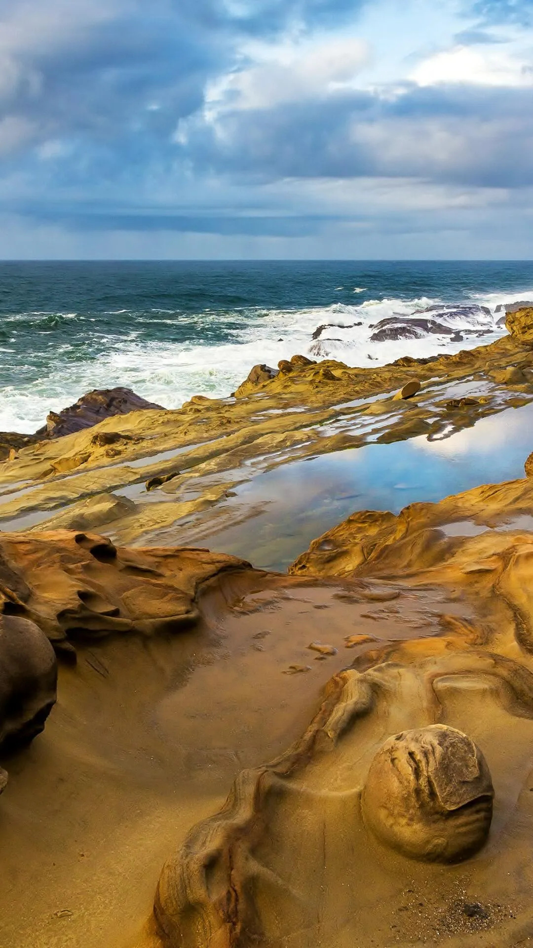 Wind Carved Coastal Rocks Beside Waves Under a Cloudy Sky