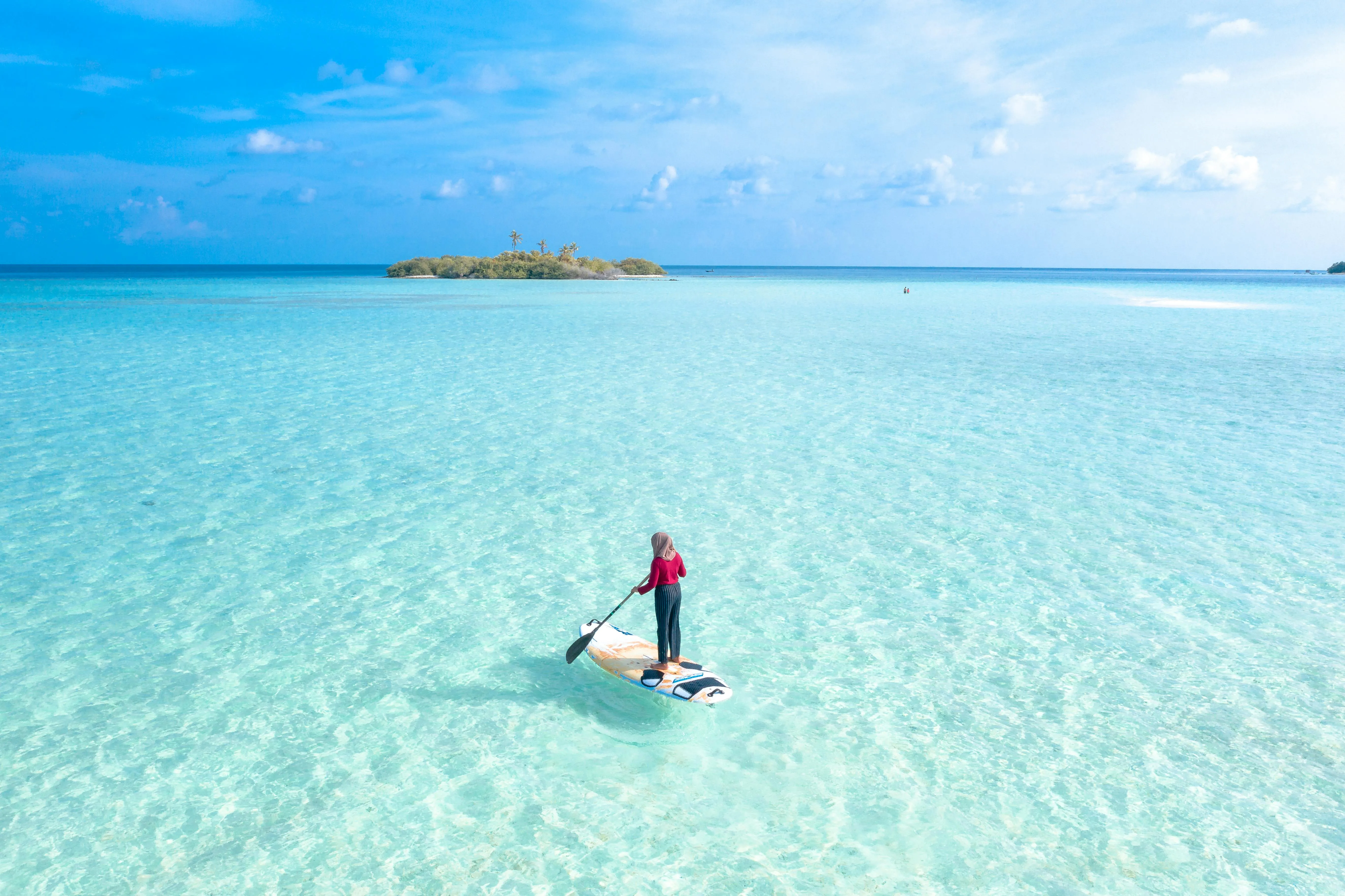 Woman Paddleboarding Across Crystal Clear Blue Waters