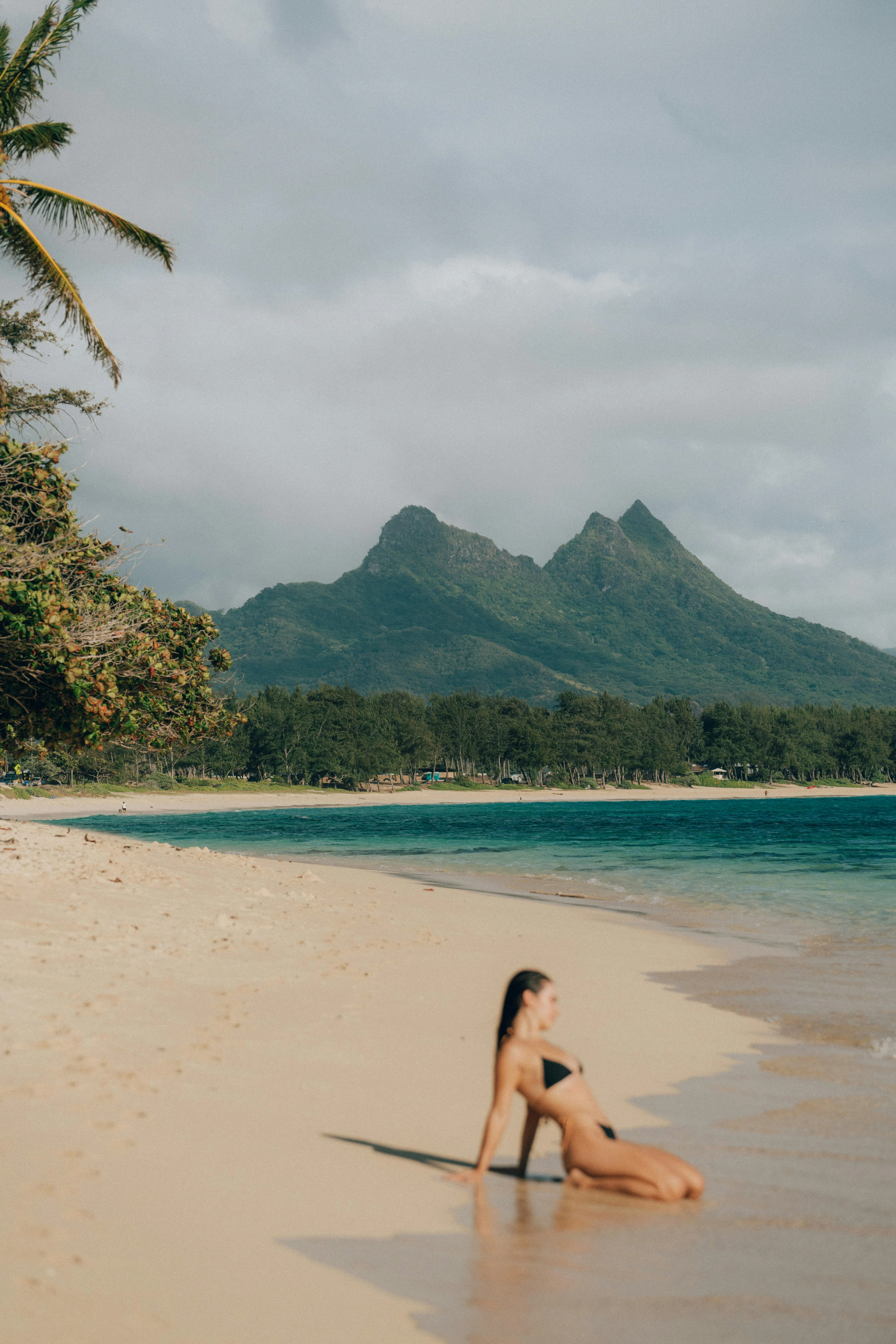 Woman Relaxes on a Quiet Beach with Tropical Mountains