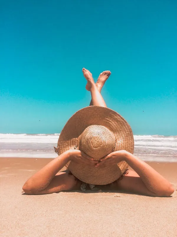 Woman Relaxing on the Beach Wearing a Large Sunhat Wallpaper