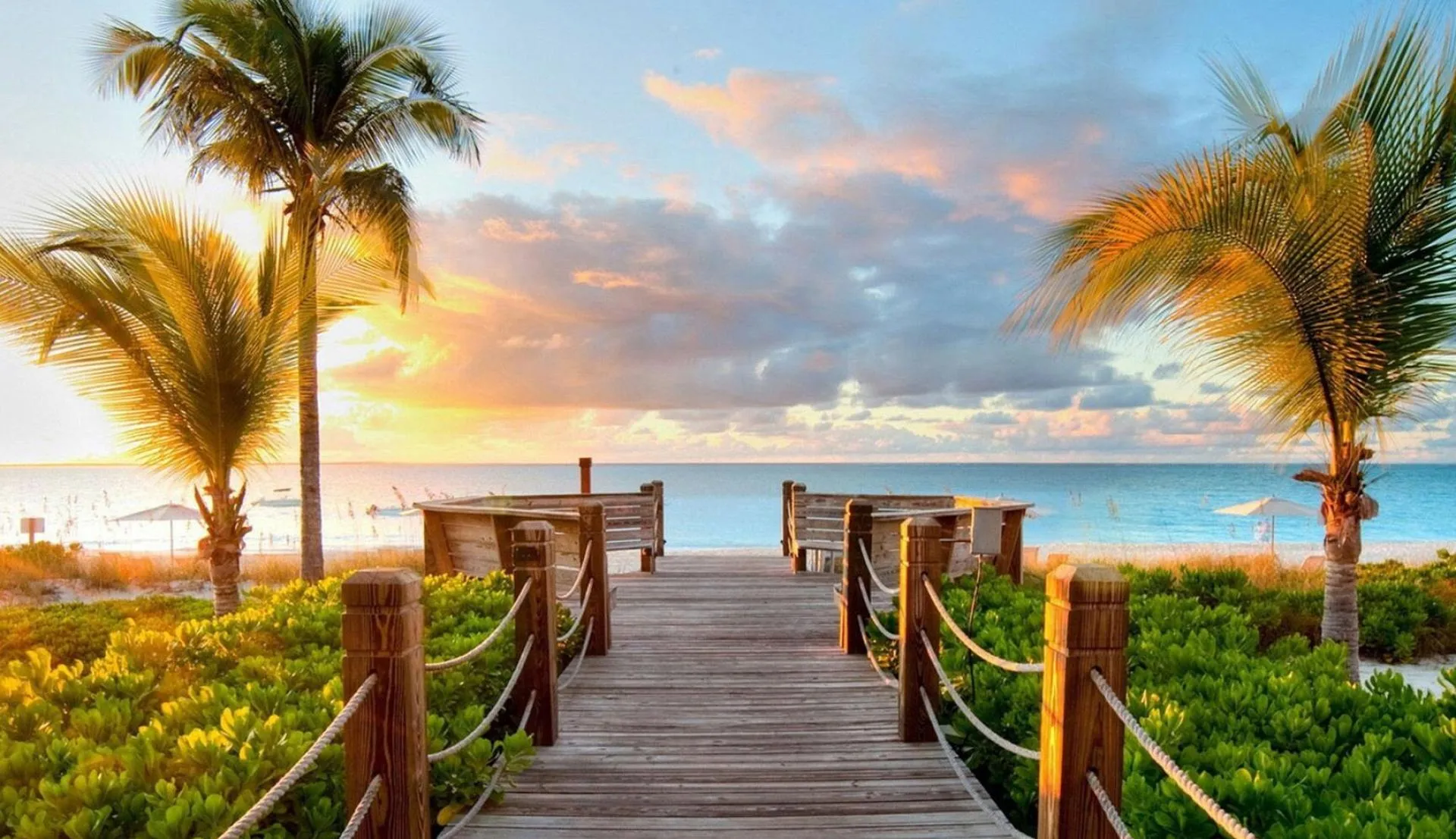 Wooden Boardwalk Leading to Sunset over a Calm Beach Shore