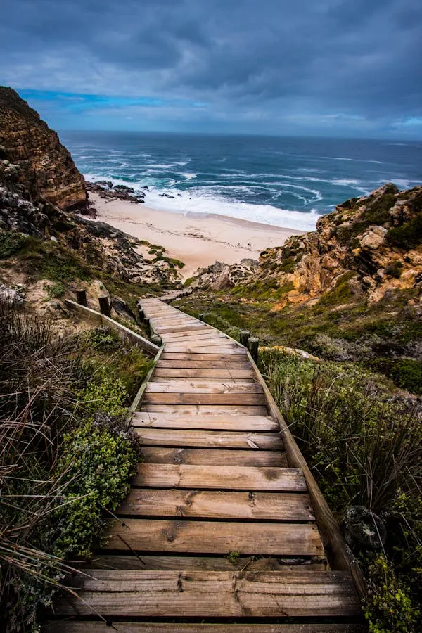 Wooden Stairs Leading Down to a Sandy Beach with Cliffs