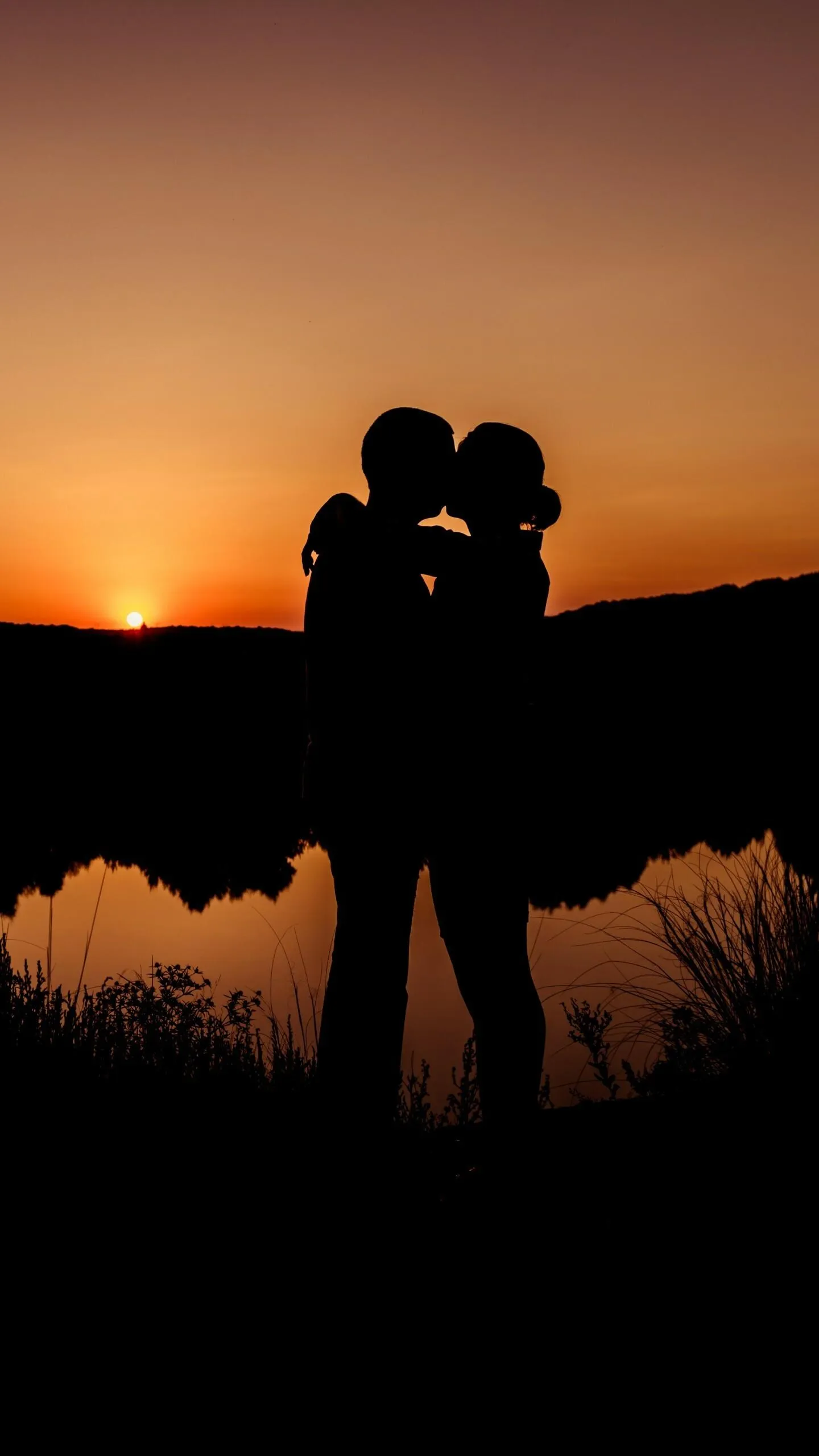 Couple Embracing Silhouette Under Warm Sunset Wallpaper