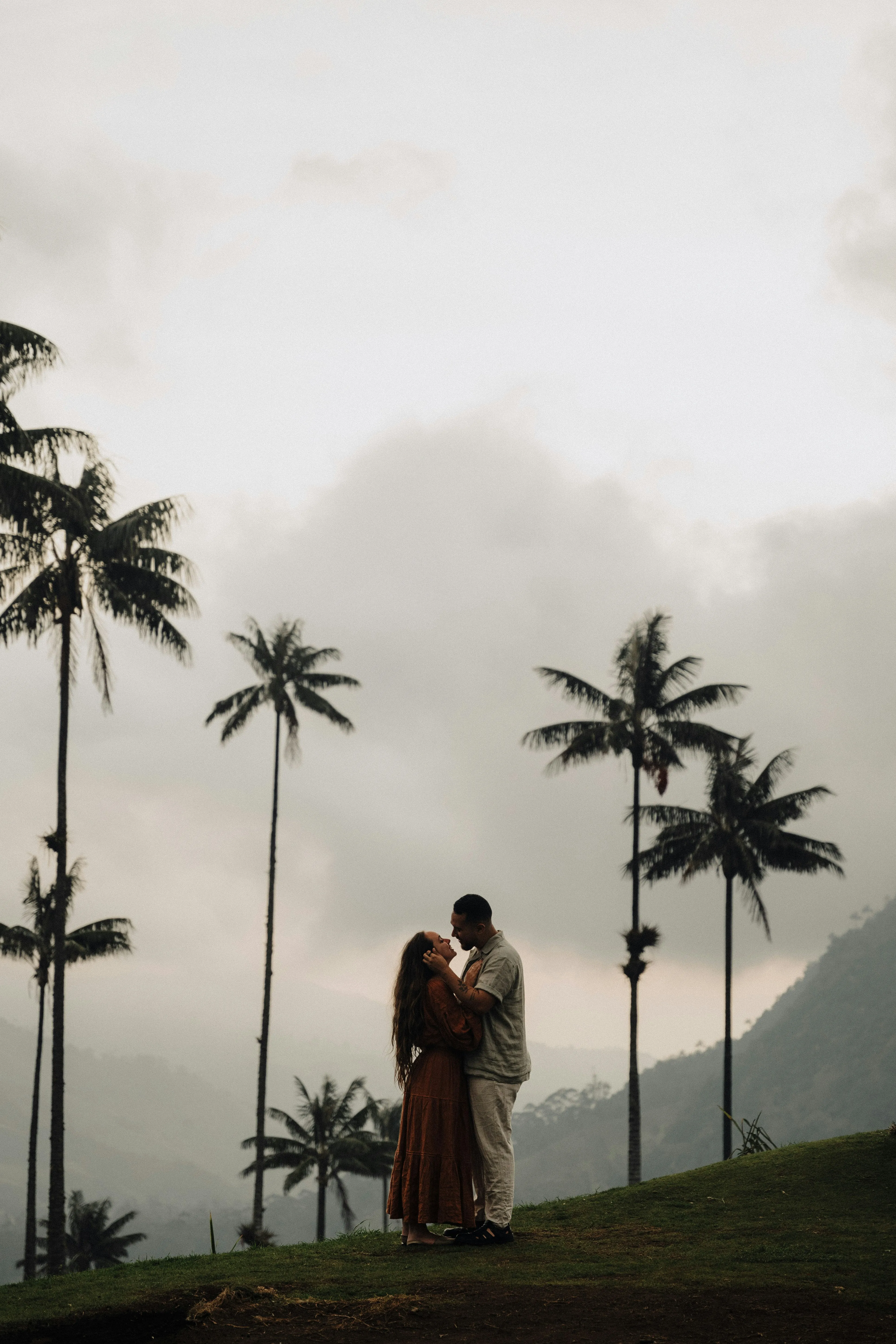 Couple Embracing Under Palm Trees at Sunset Wallpaper