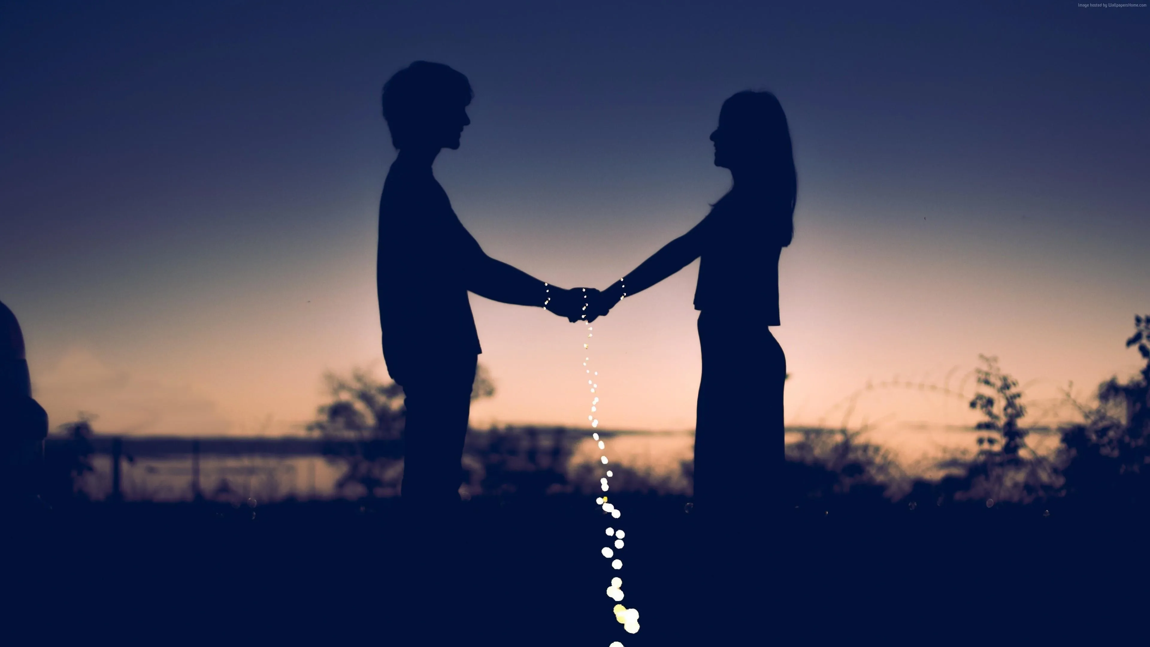 Couple Holding Hands at Golden Sunset Moment Wallpaper