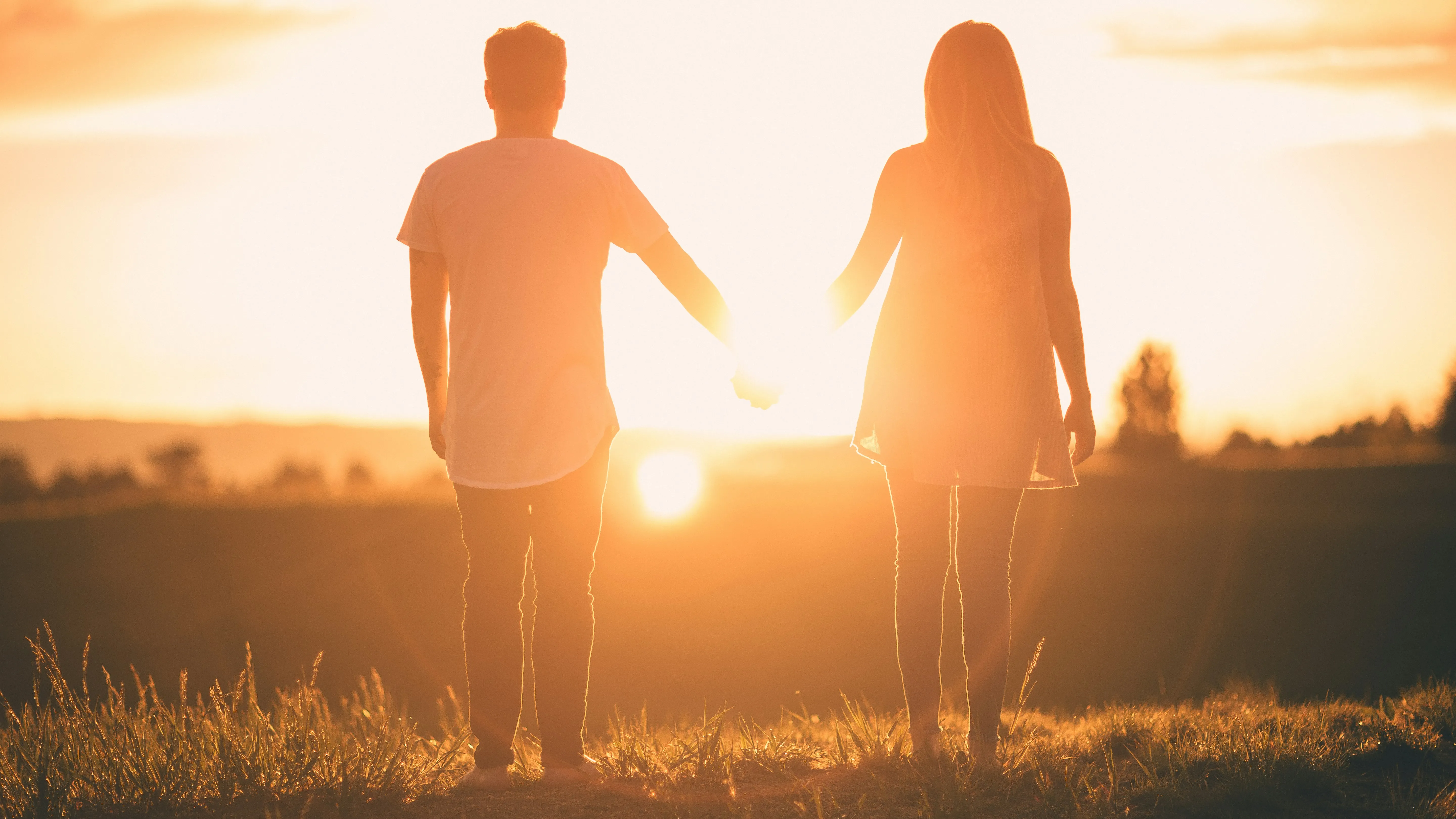 Couple Holding Hands While Walking at Sunset Wallpaper