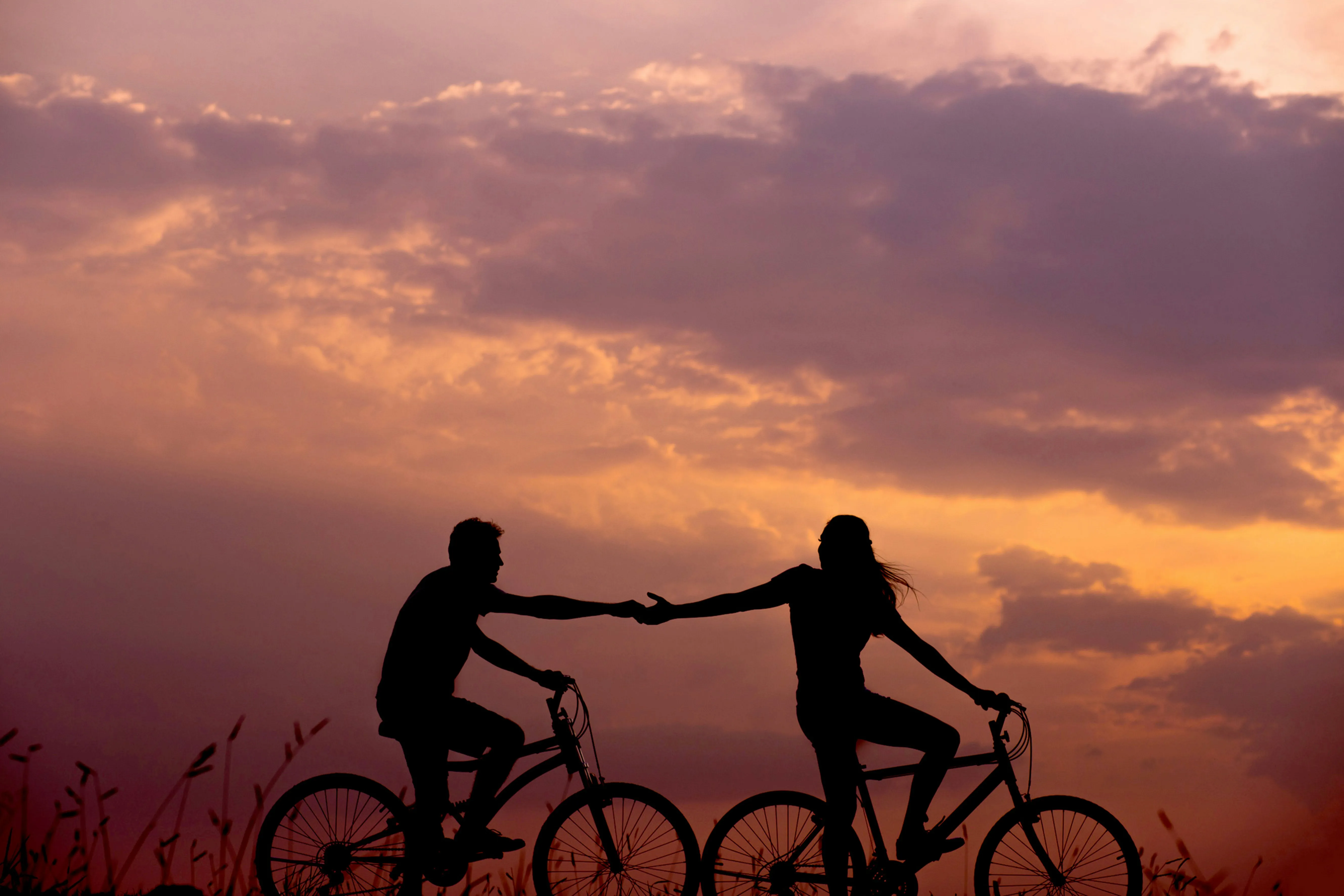 Couple Riding Bicycles Together at Golden Sunset Wallpaper