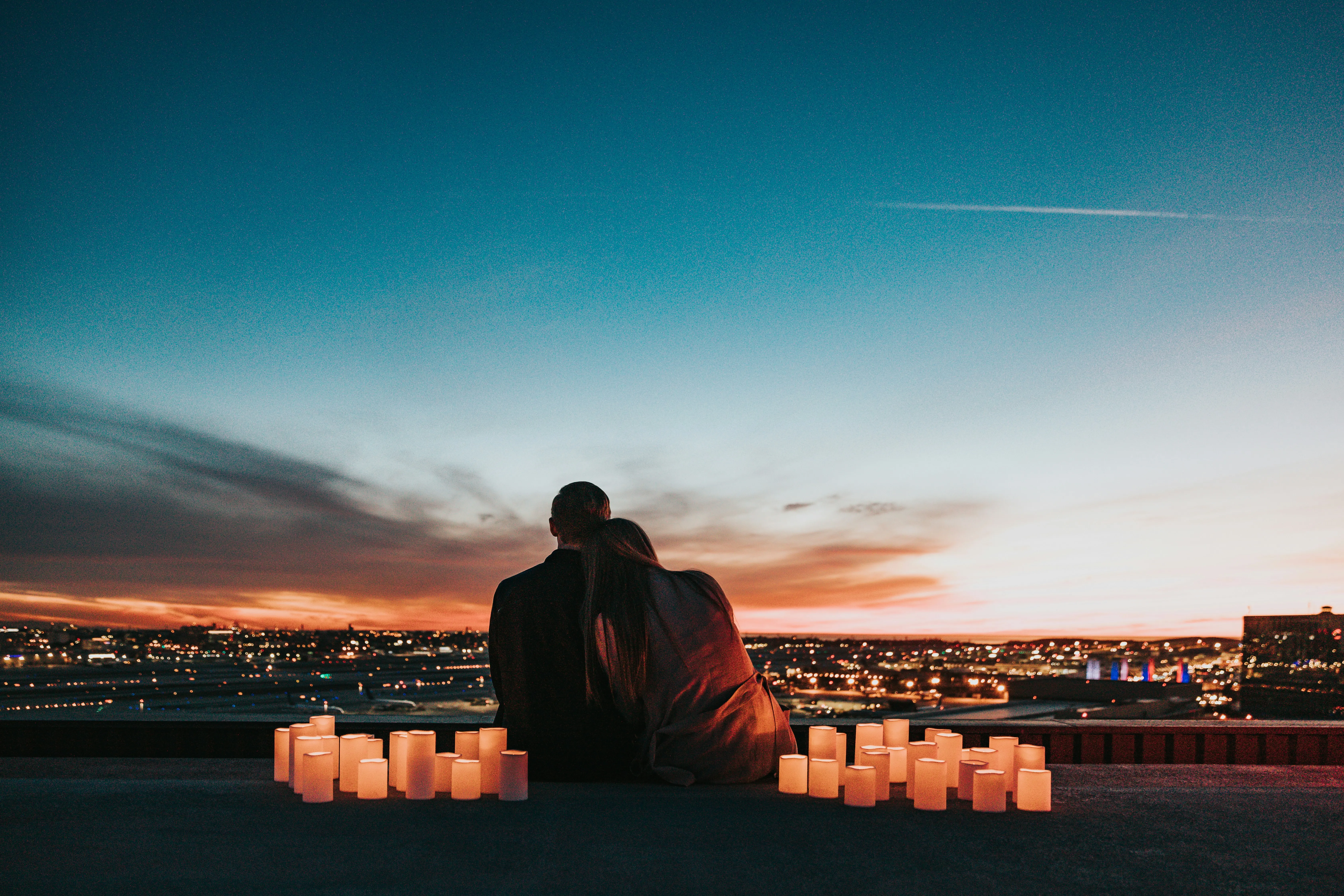 Couple Sitting Together Watching City Sunset Glow Wallpaper