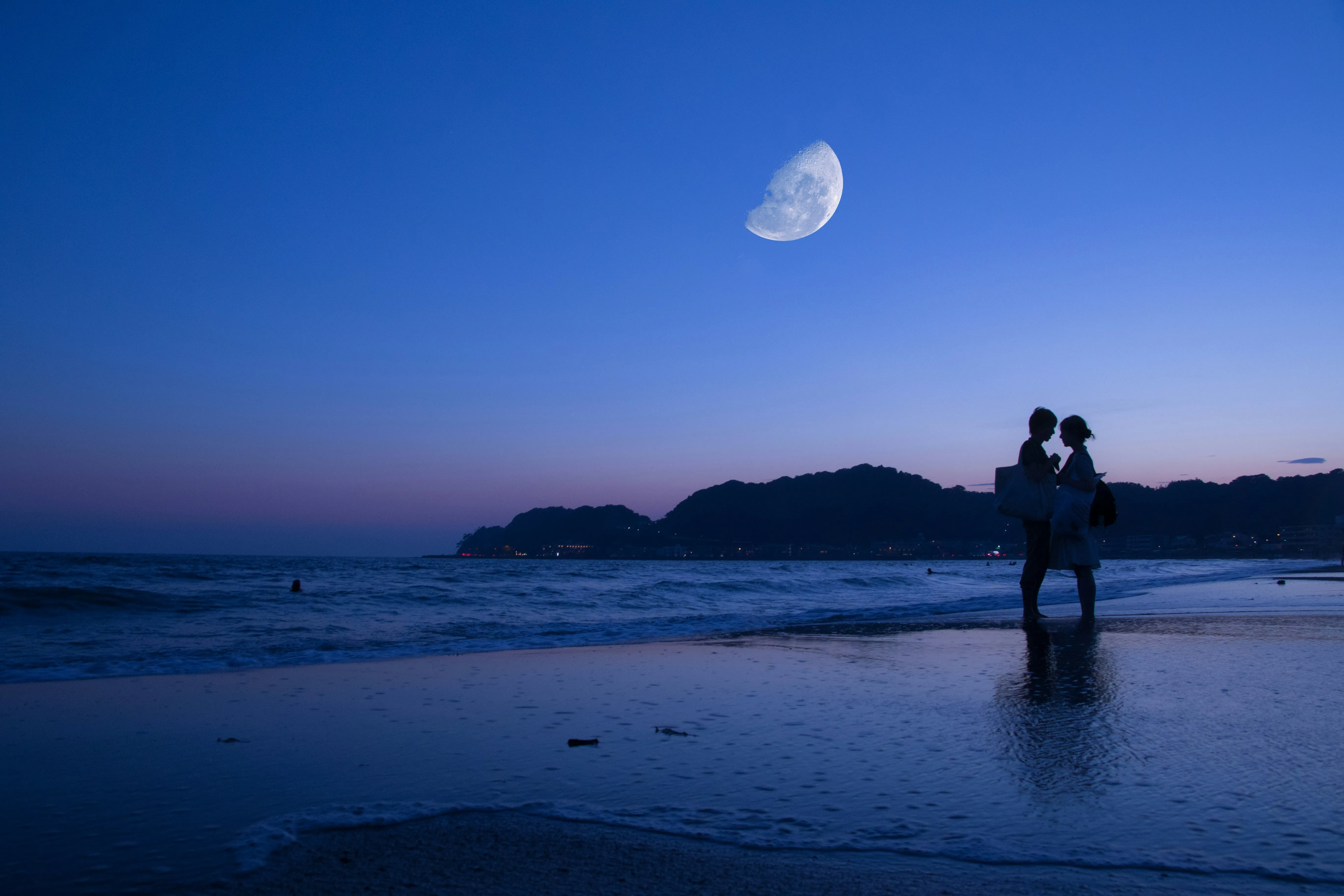 Couple Standing Under Moonlight Near Ocean Waves Wallpaper