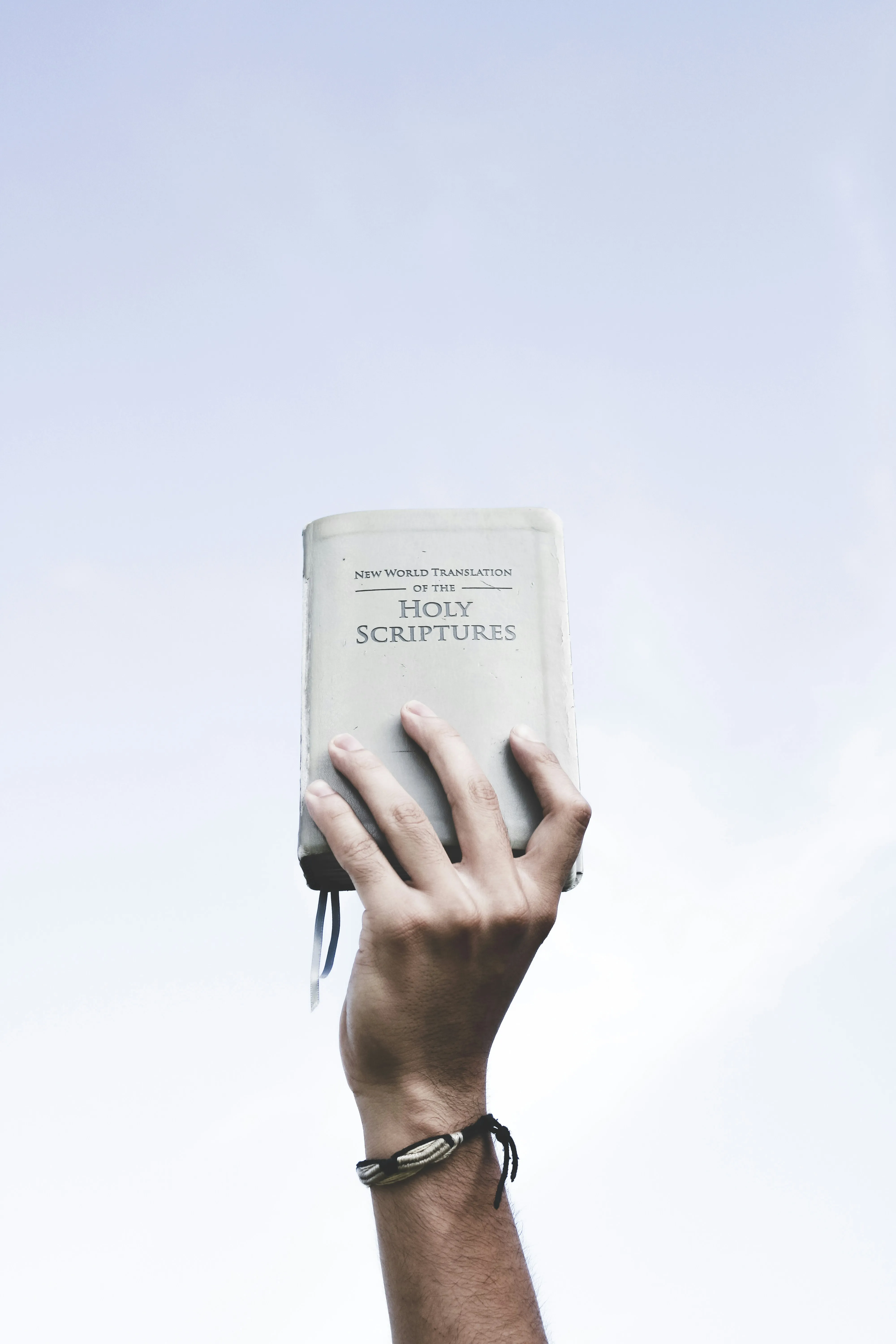 Hand Holding Bible Toward Bright Blue Sky Wallpaper