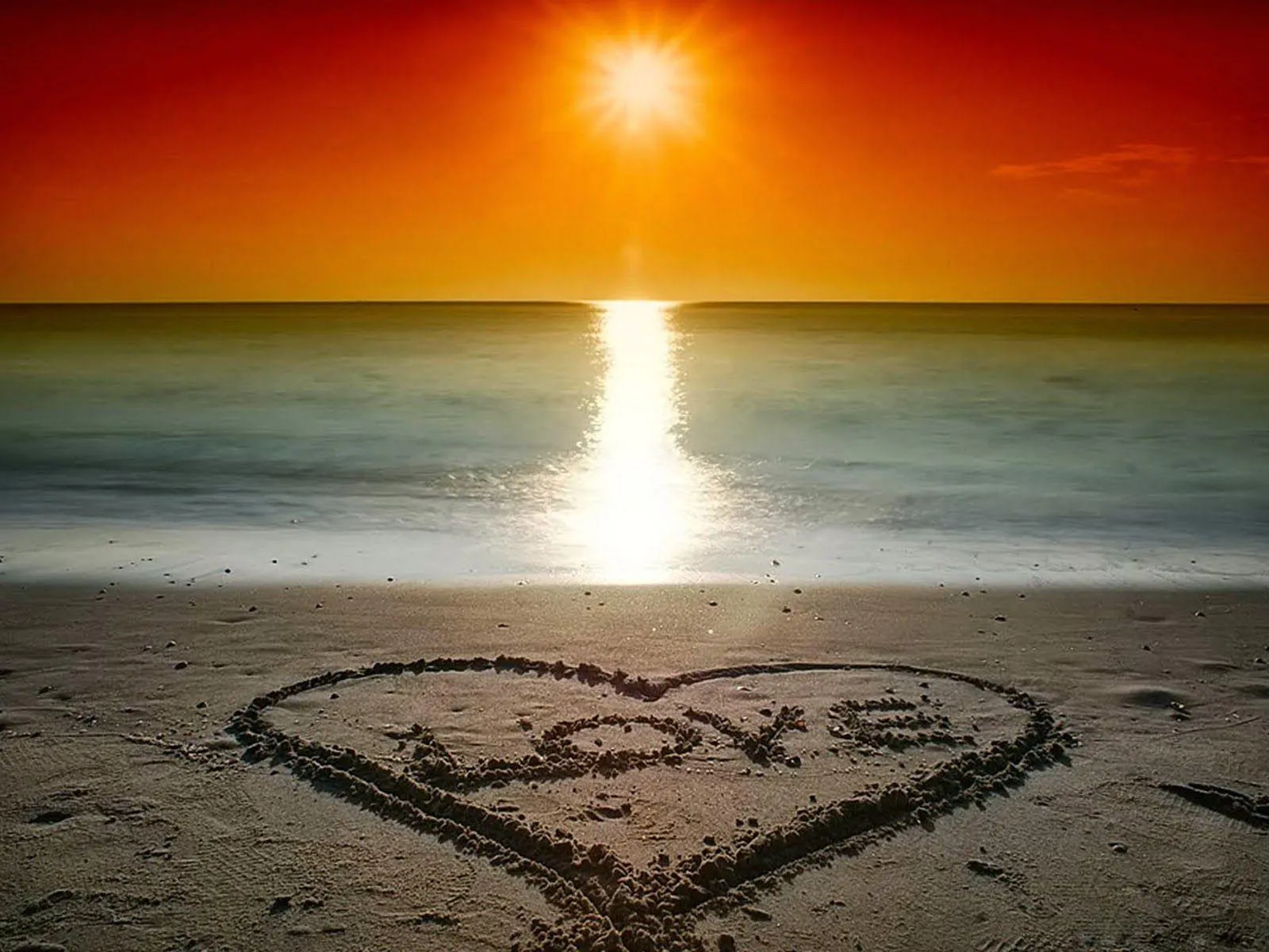 Heart Drawn on Beach Sand at Golden Sunset Wallpaper