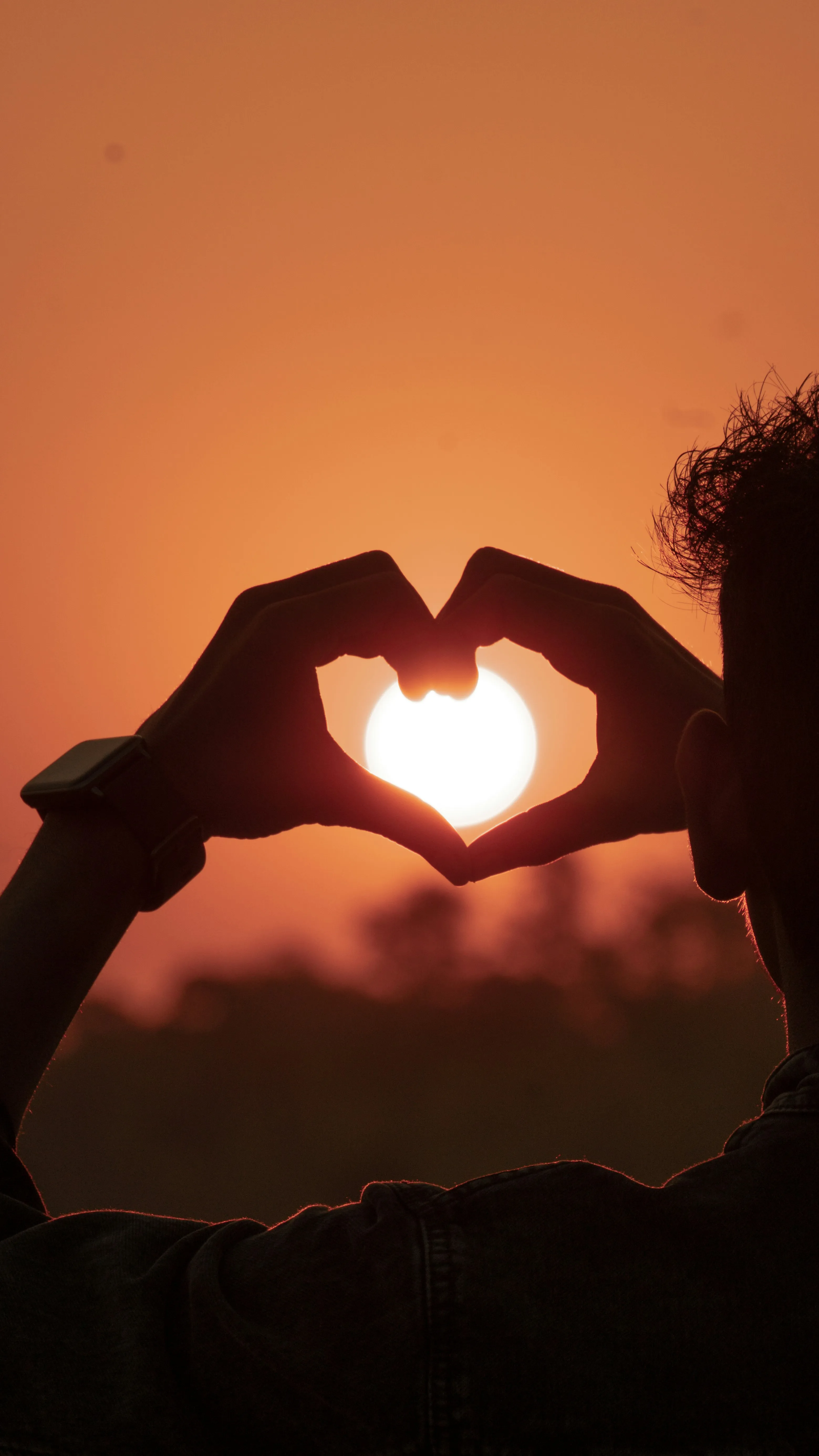 Heart Hand Silhouette Against a Golden Sunset Wallpaper