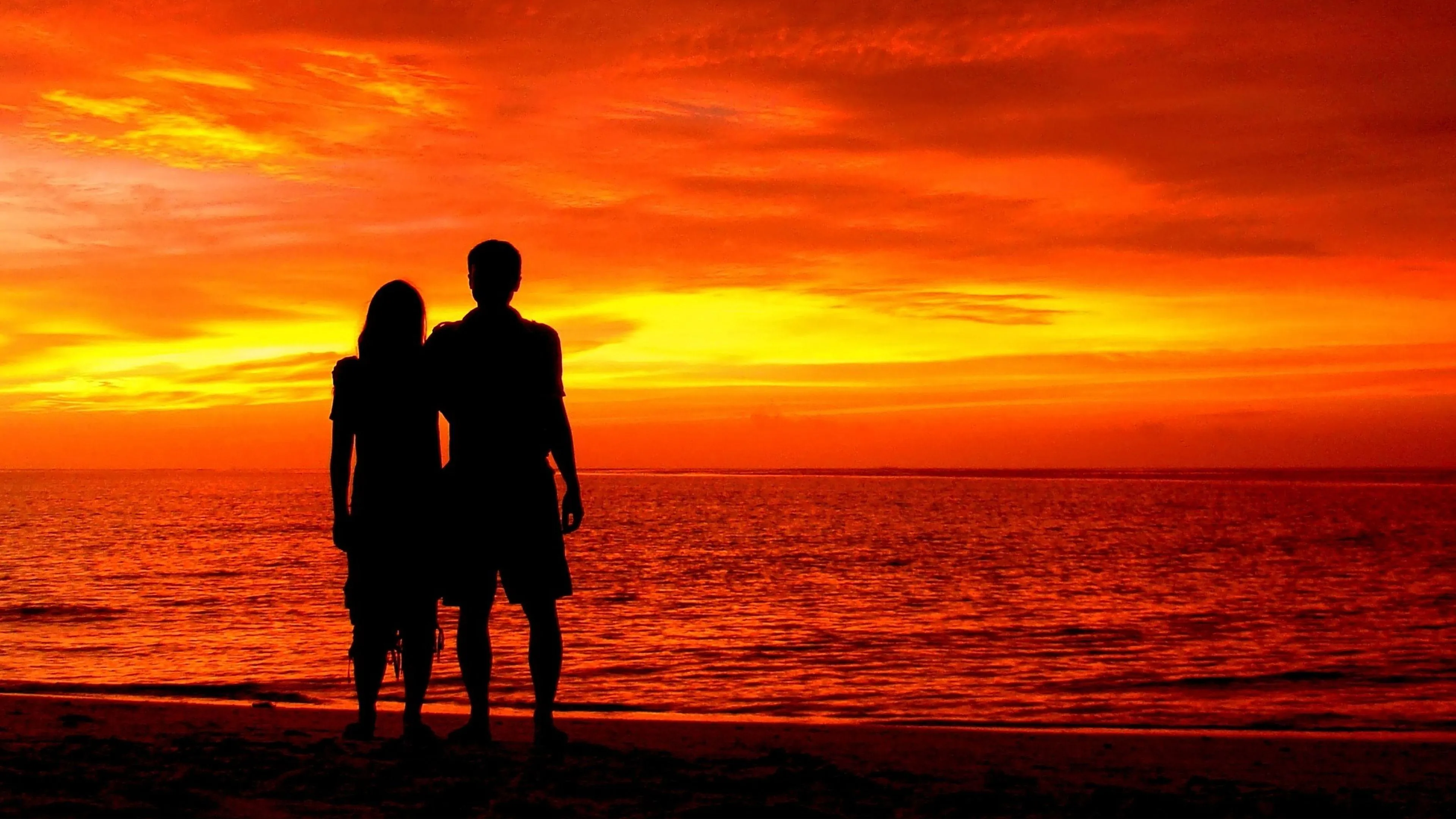 Image of Couple Watching Sunset on Beach with Warm Light