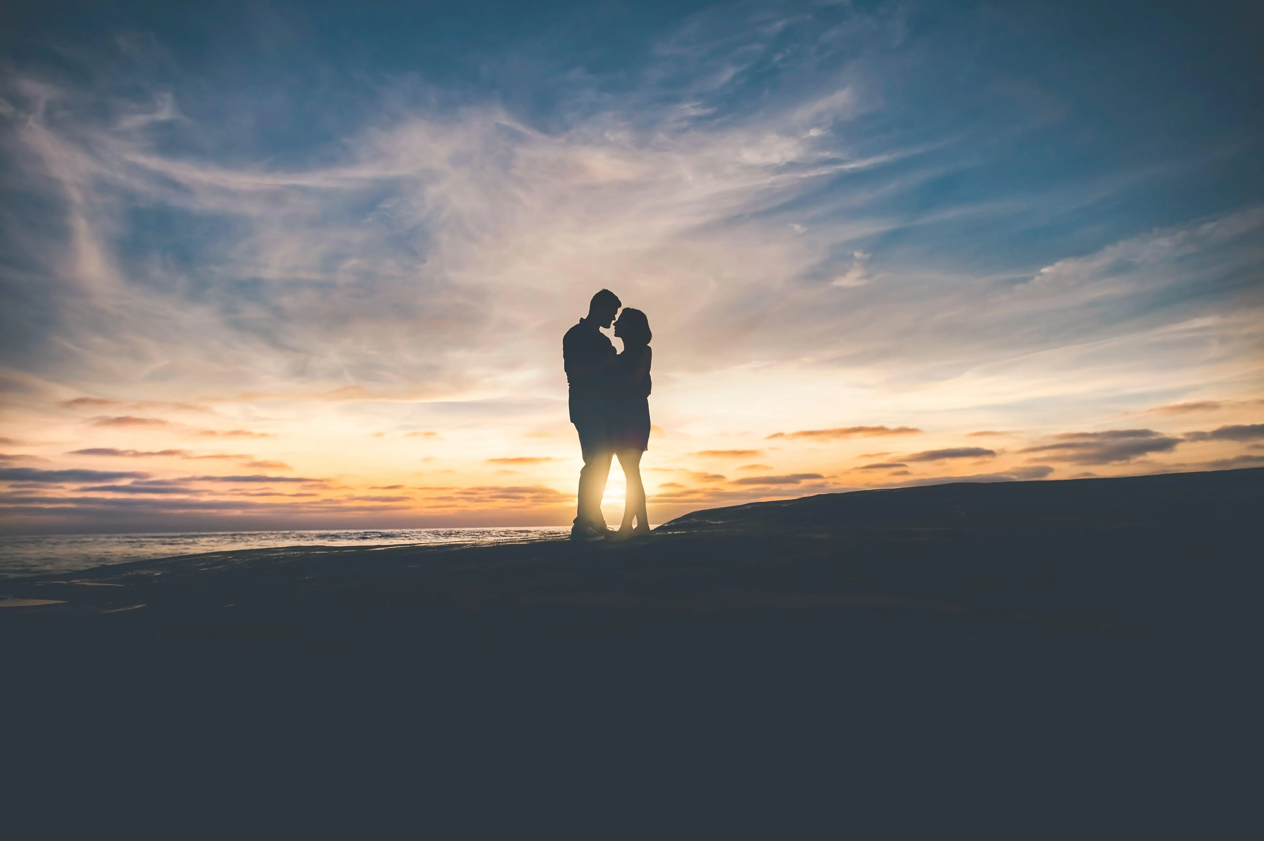 Lonely Couple Standing Under Golden Sunset Sky Wallpaper