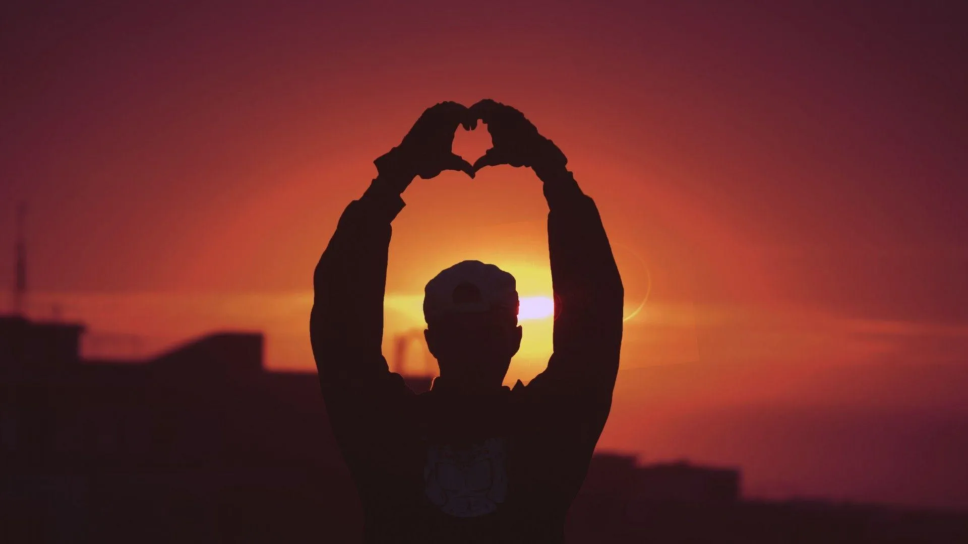 Man Creating Heart Shape with Evening Sunset Wallpaper
