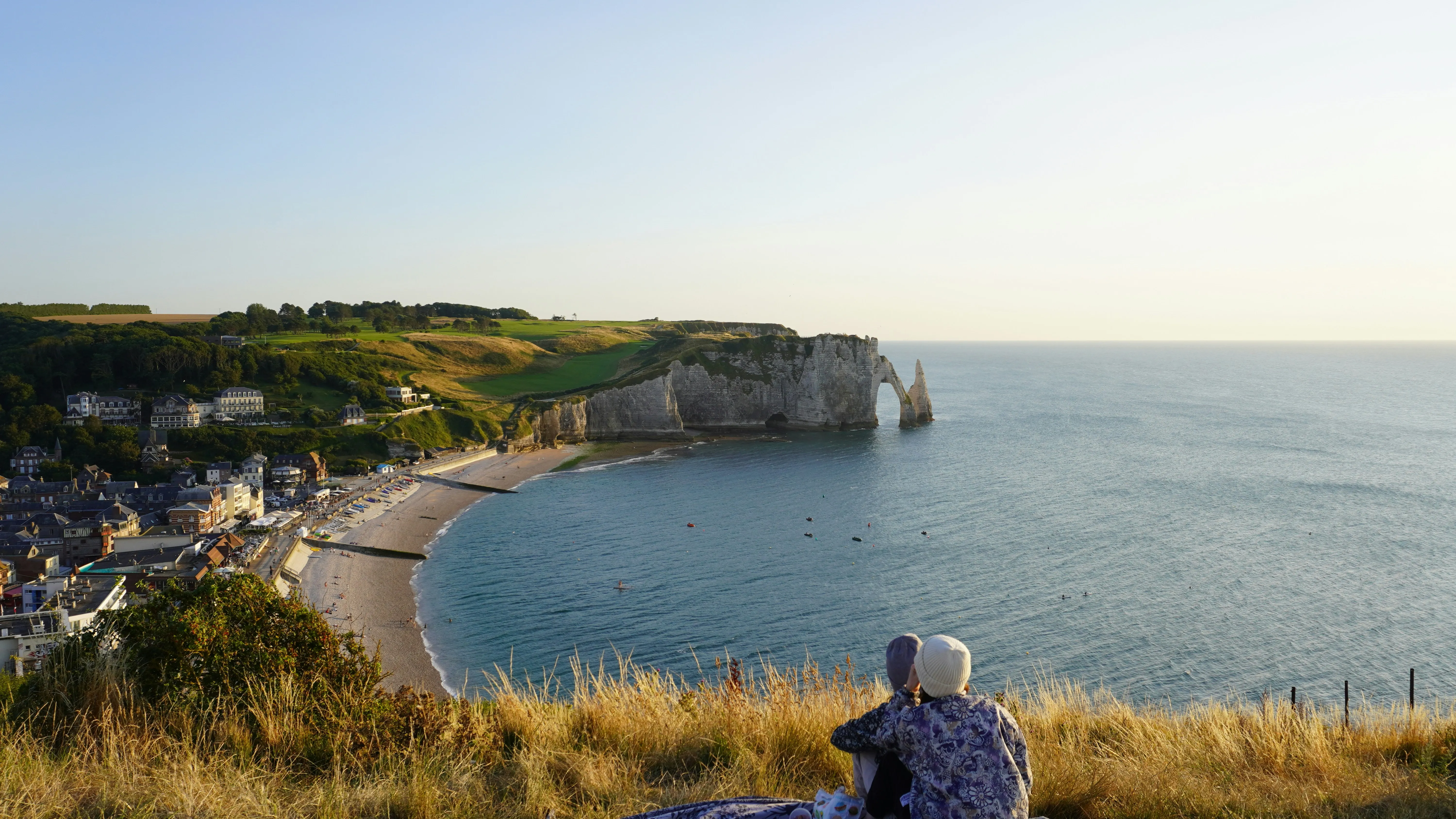 Man Sitting on Cliff Watching Serene Ocean View Wallpaper