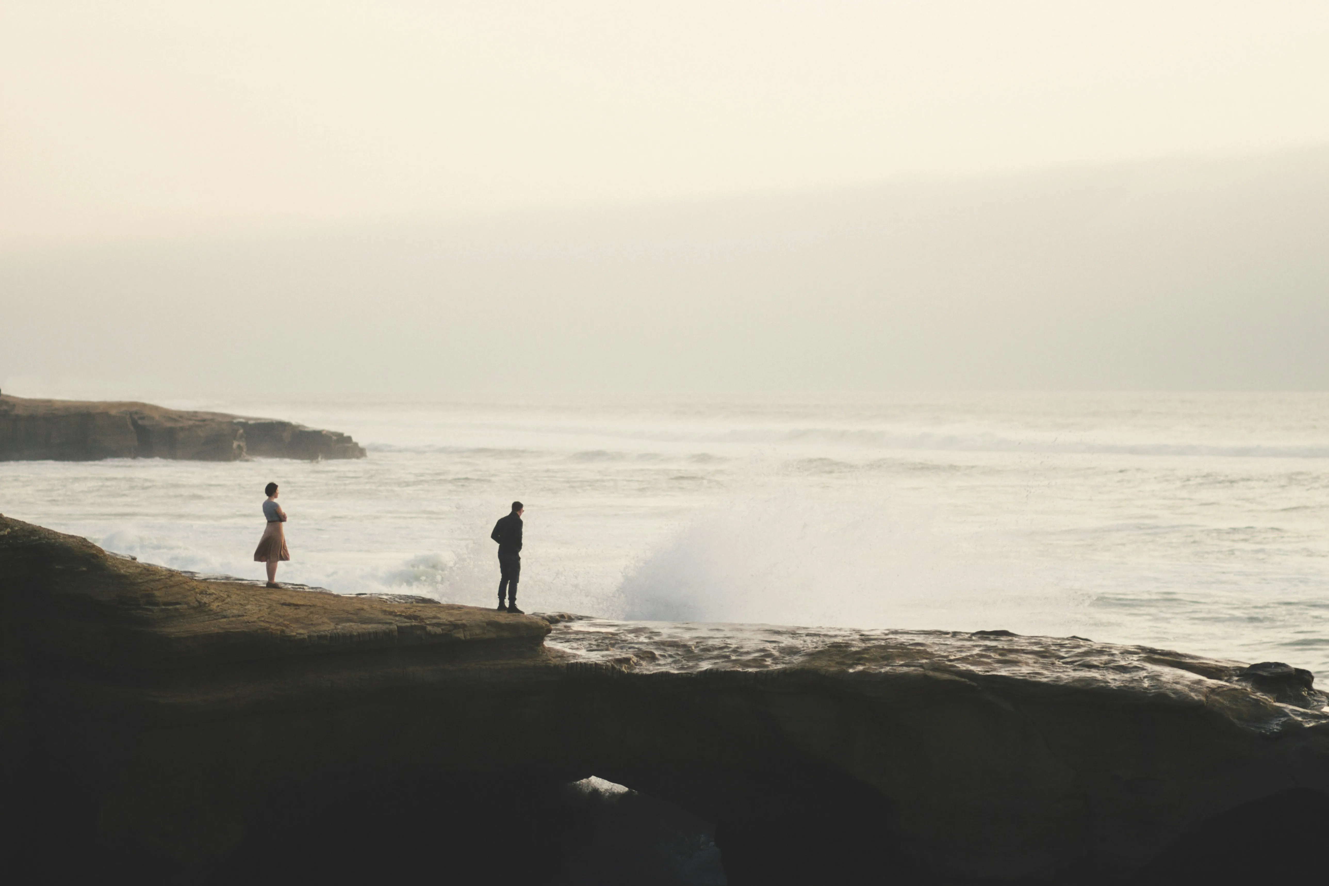 People Walking Along Beach Shoreline at Sunset Wallpaper