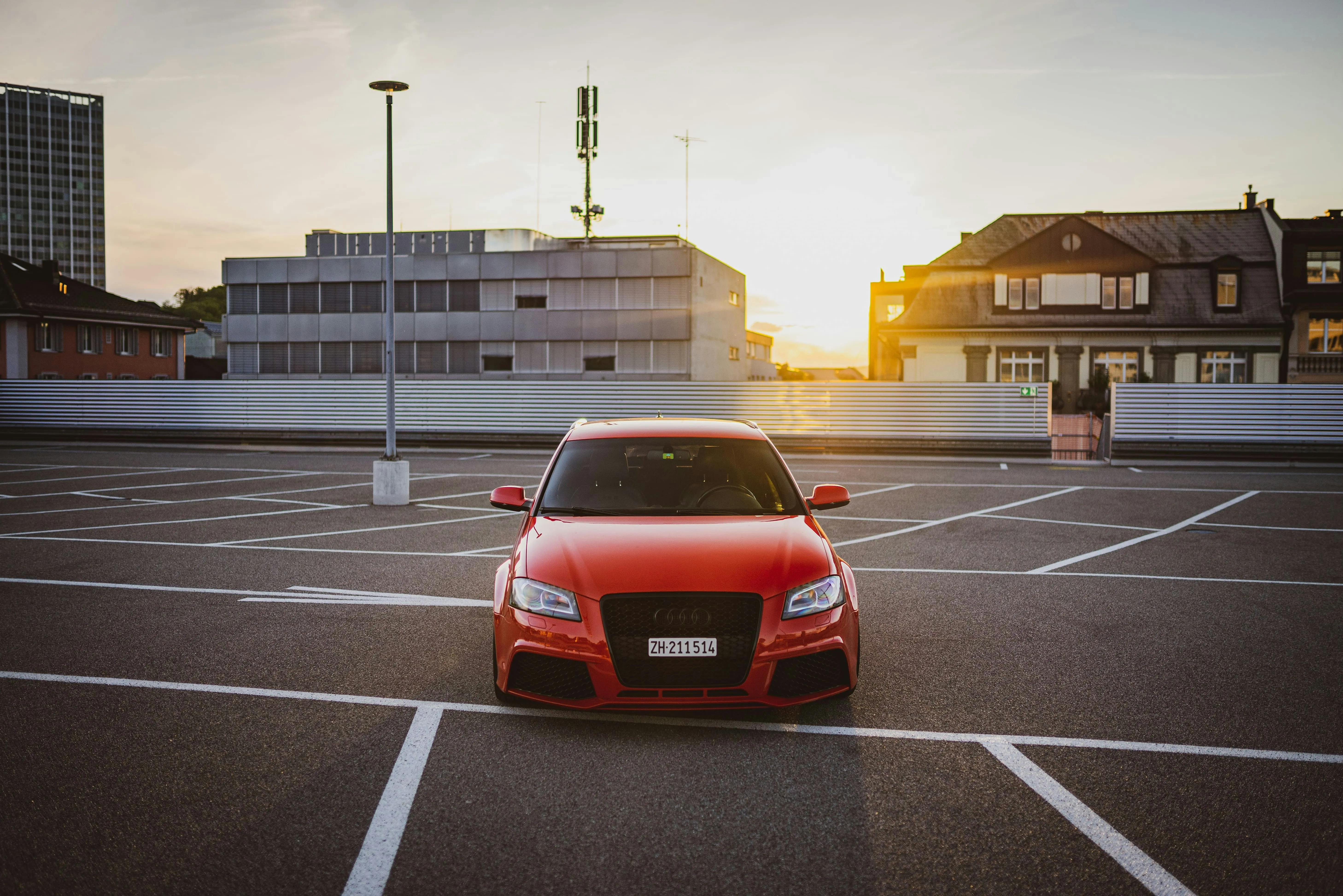 Red Car in Empty Parking Lot Under Evening Light Wallpaper