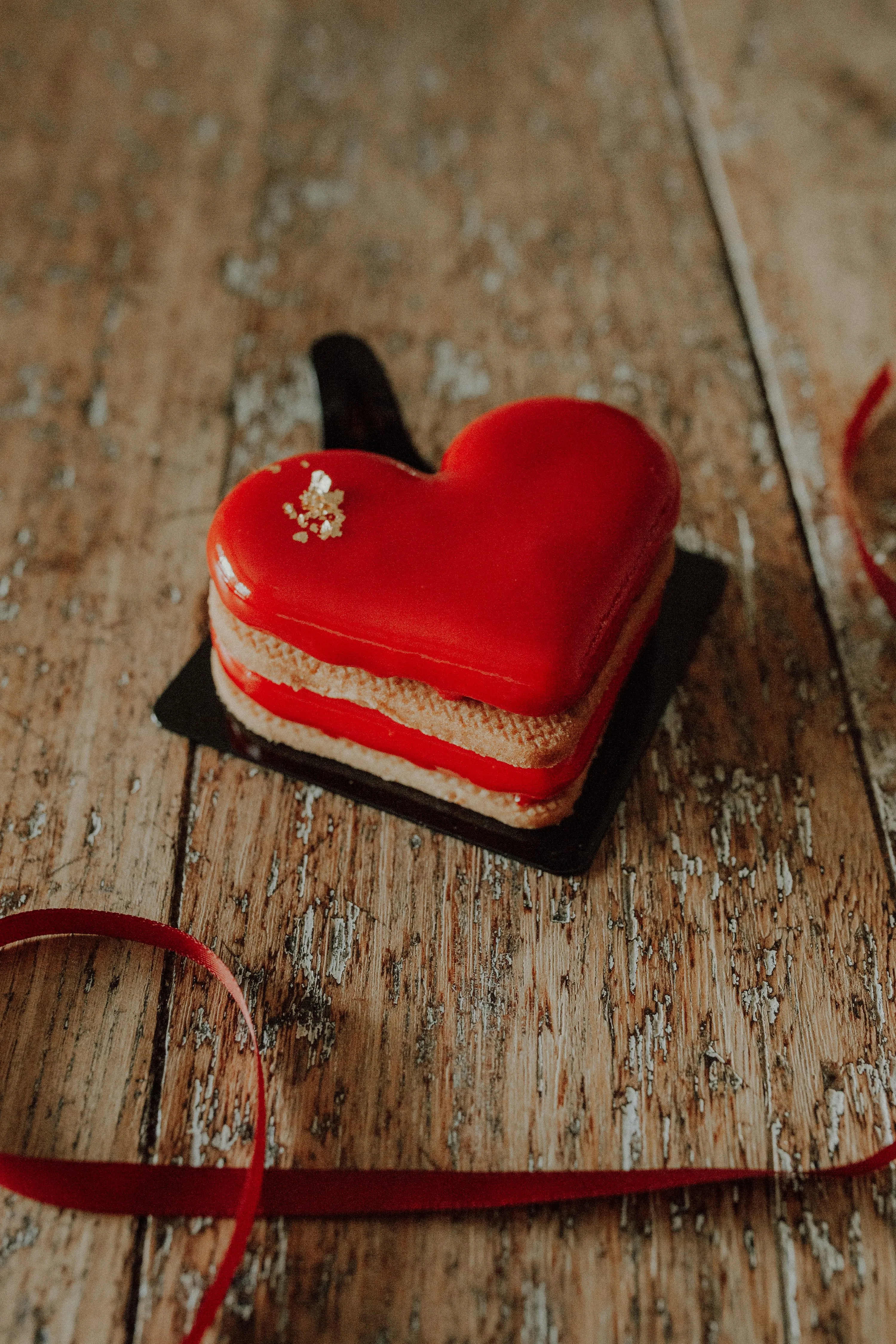 Red Heart Cookie Resting on Wooden Tabletop Wallpaper