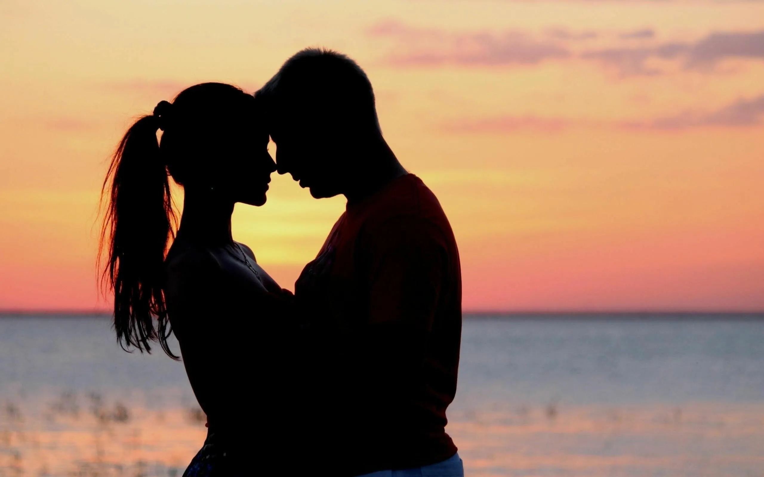 Silhouette Couple Kissing at a Warm Sunset Beach Wallpaper