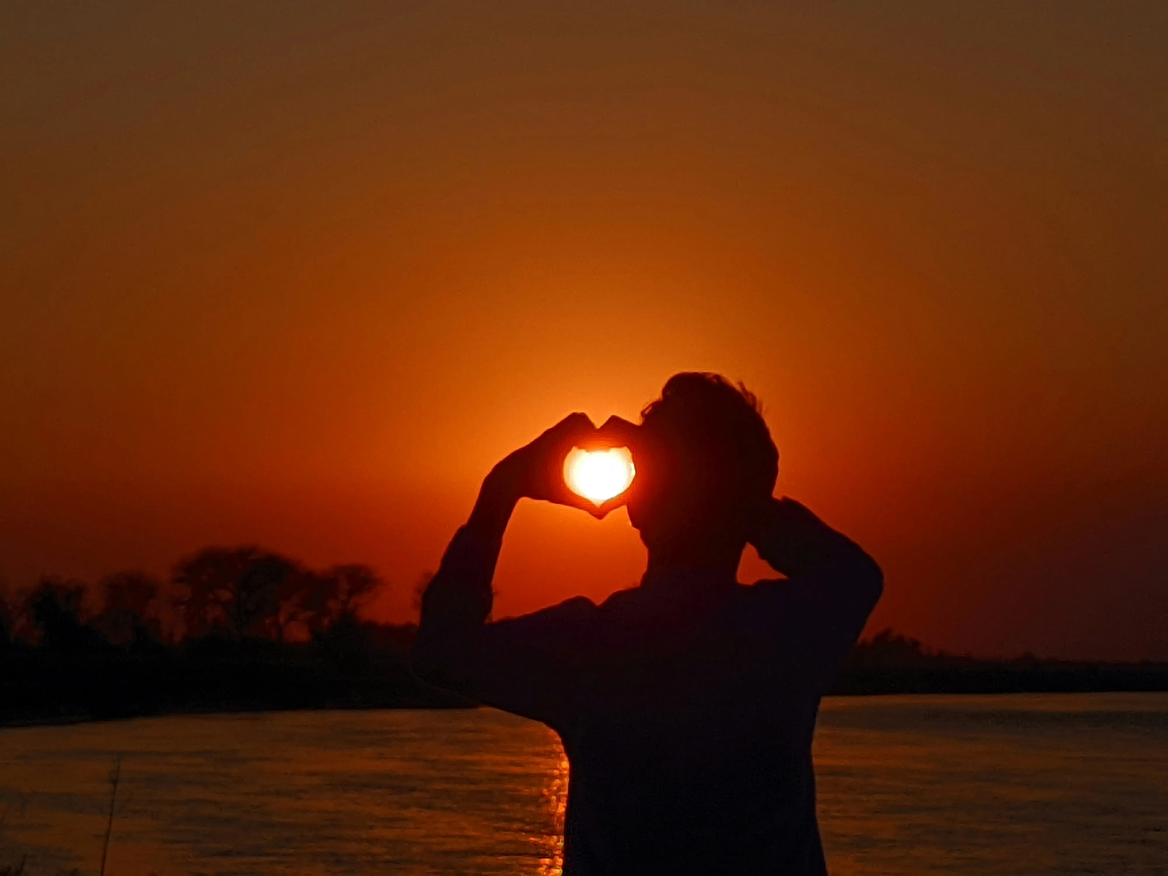 Silhouette Hands Forming Heart at Sunset Wallpaper