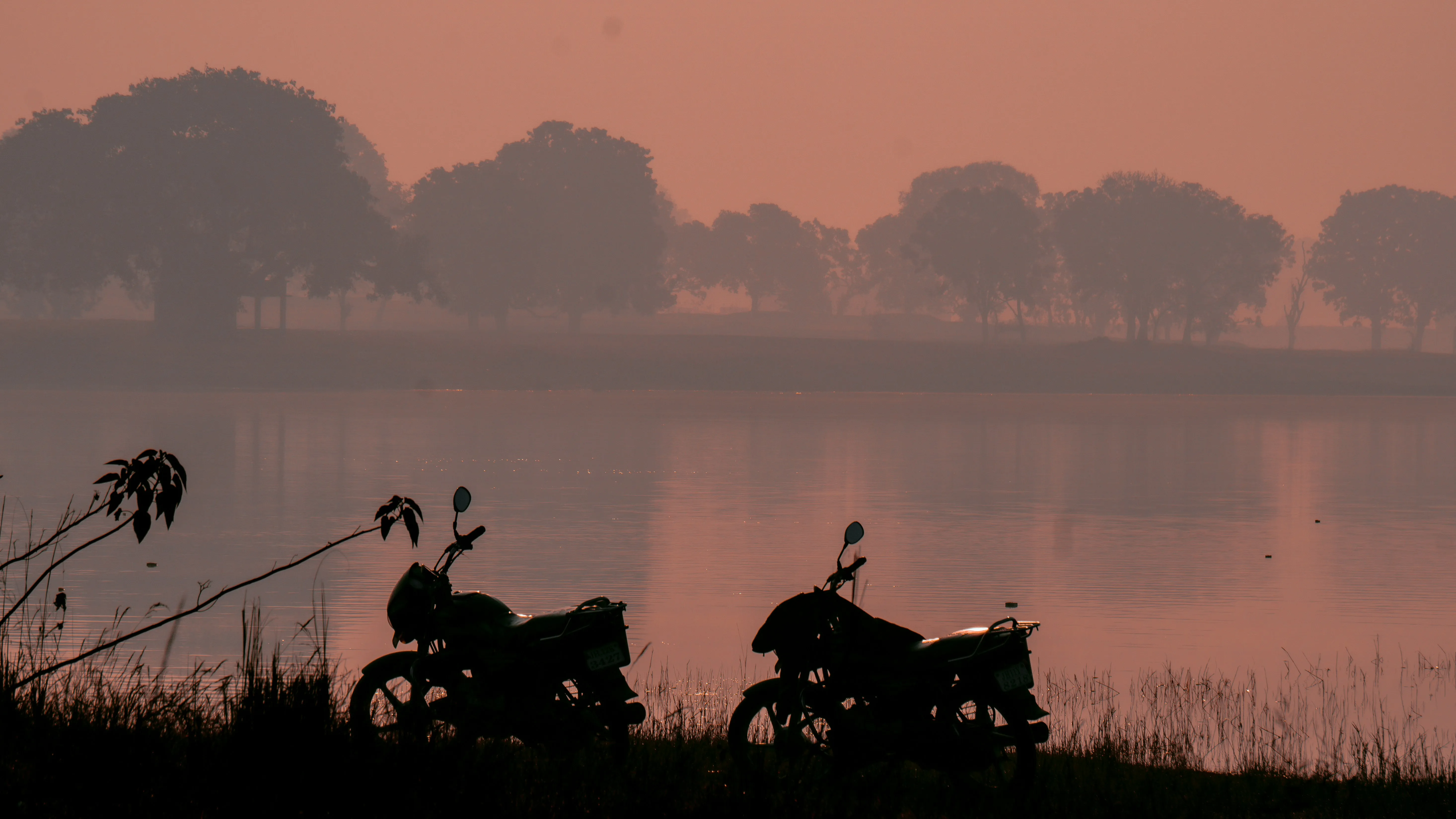 Silhouette of Bikes Reflected on Calm Lake Water Wallpaper