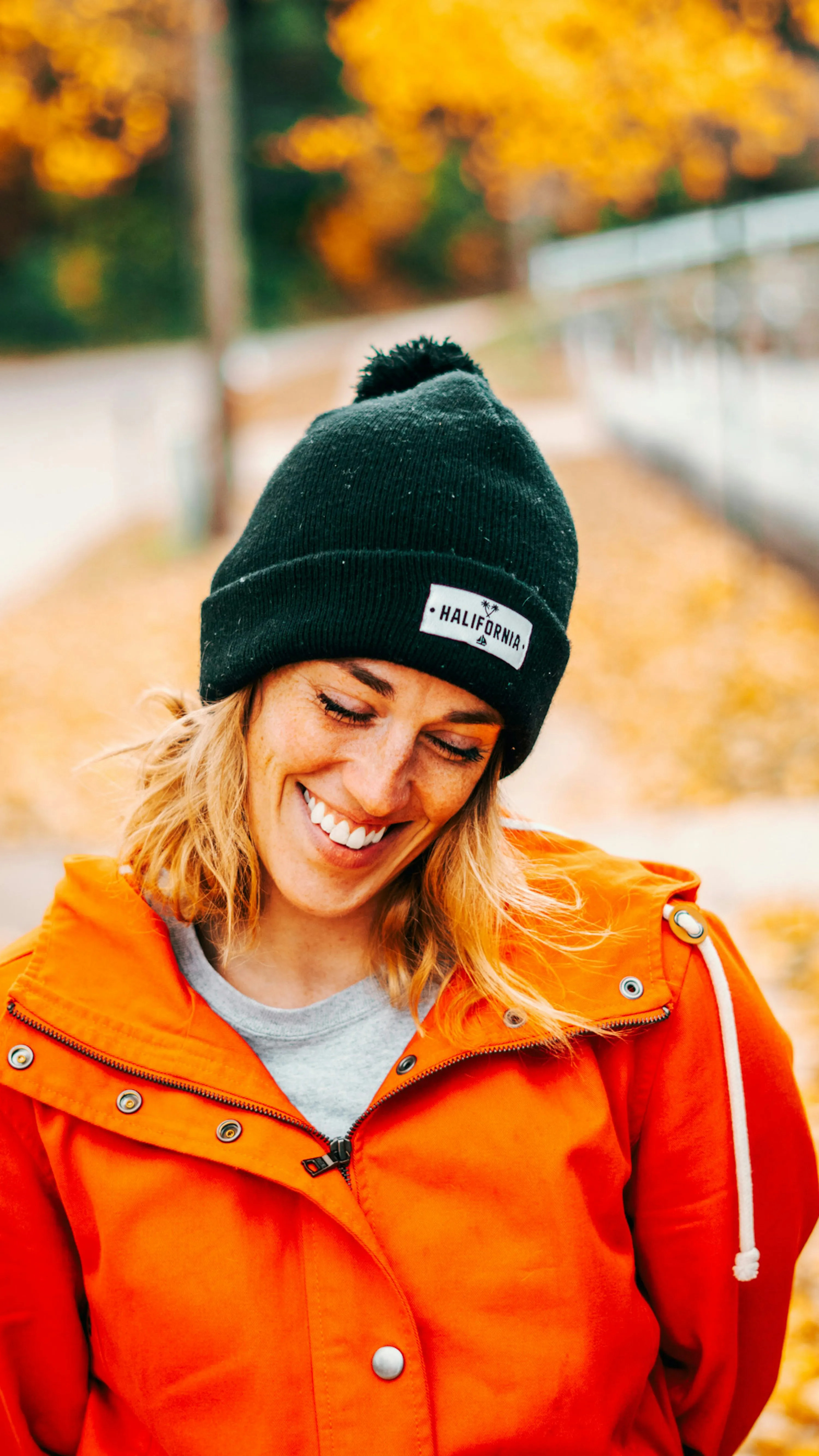 Smiling Woman in Orange Jacket Radiating Warm Joy Wallpaper