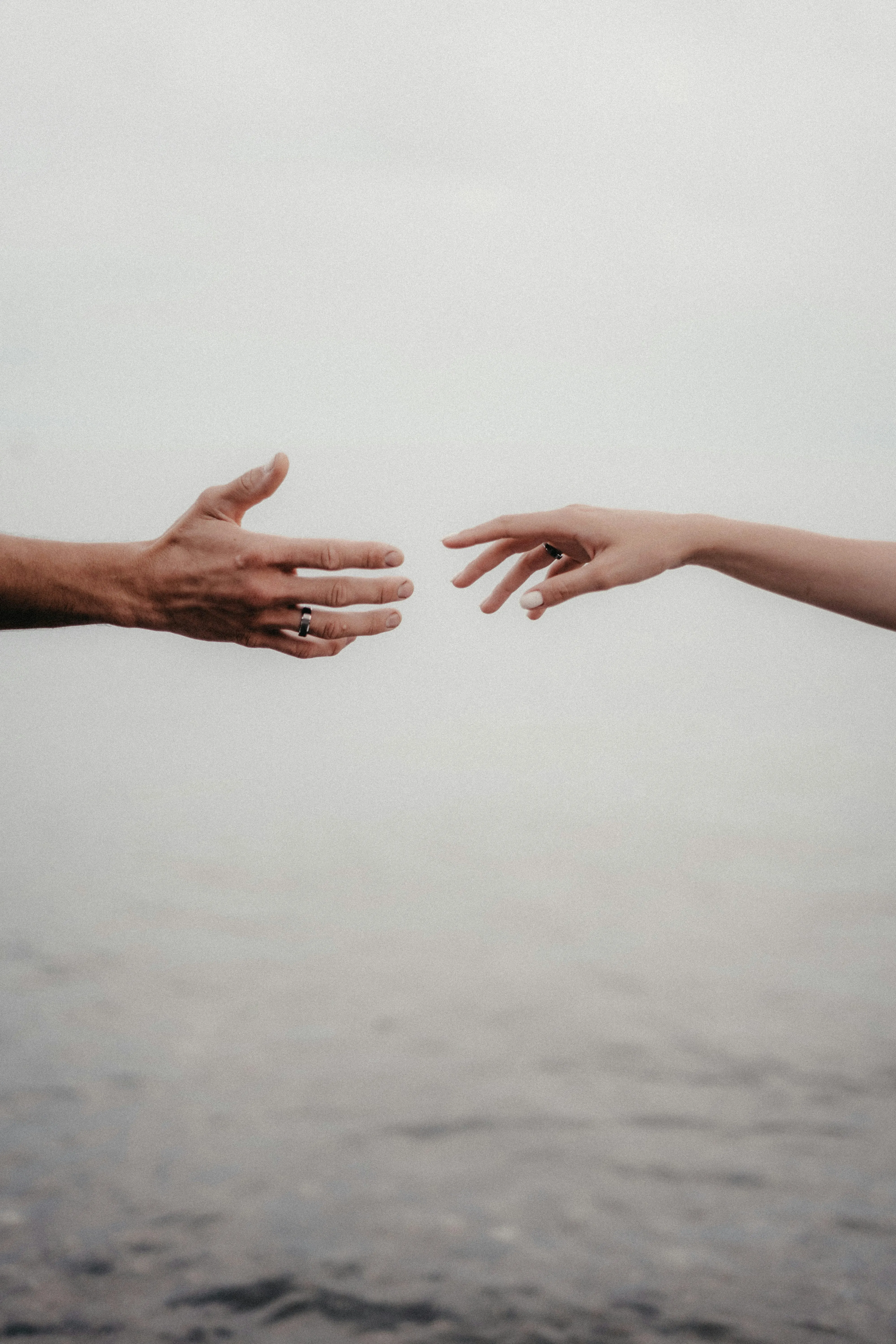 Two Hands Reaching Toward Each Other in Soft Light Wallpaper