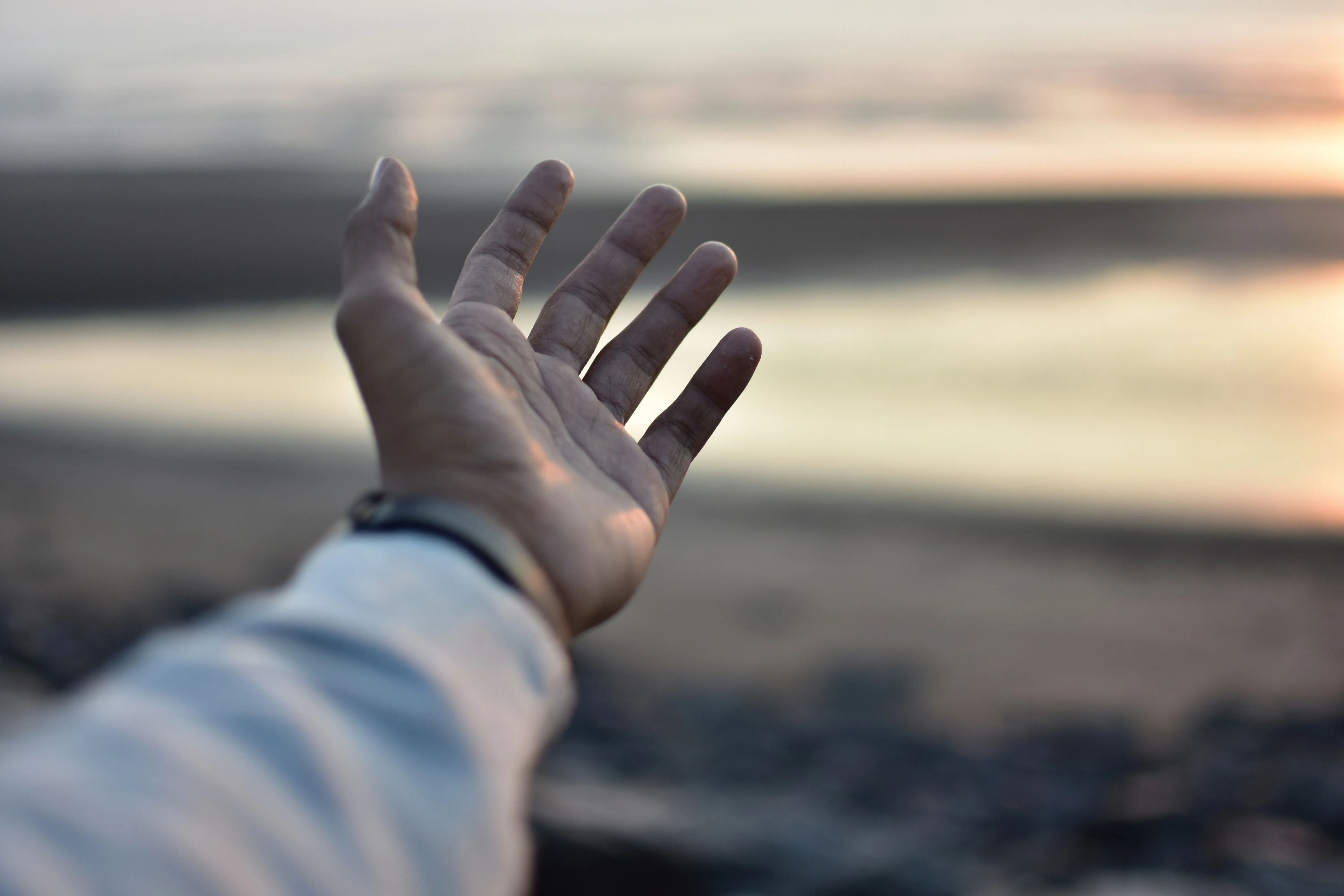 Wallpaper of Hand Reaching Toward Horizon at Golden Sunset