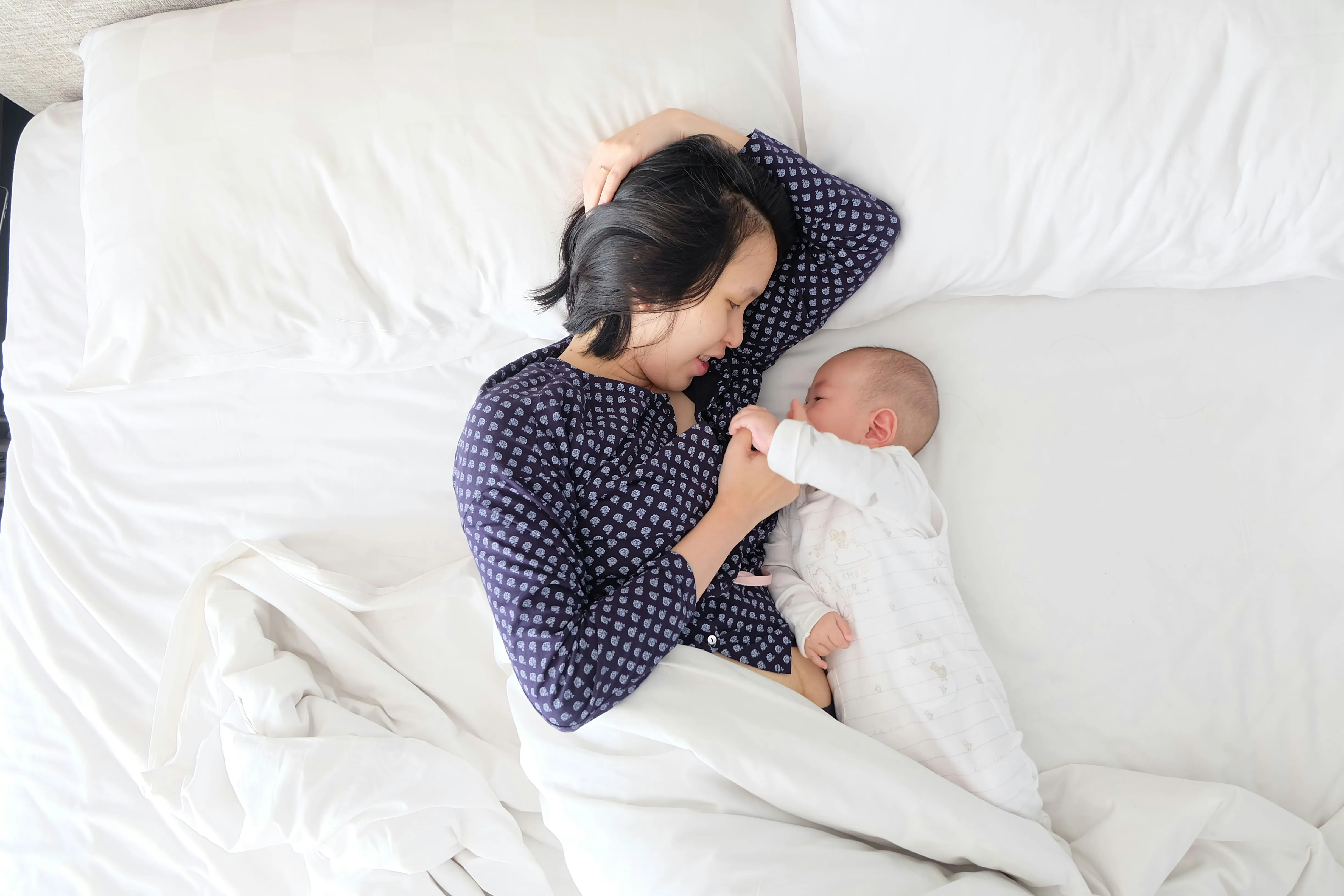 Woman Resting on Bed with Baby Showing Calm Loving Mood