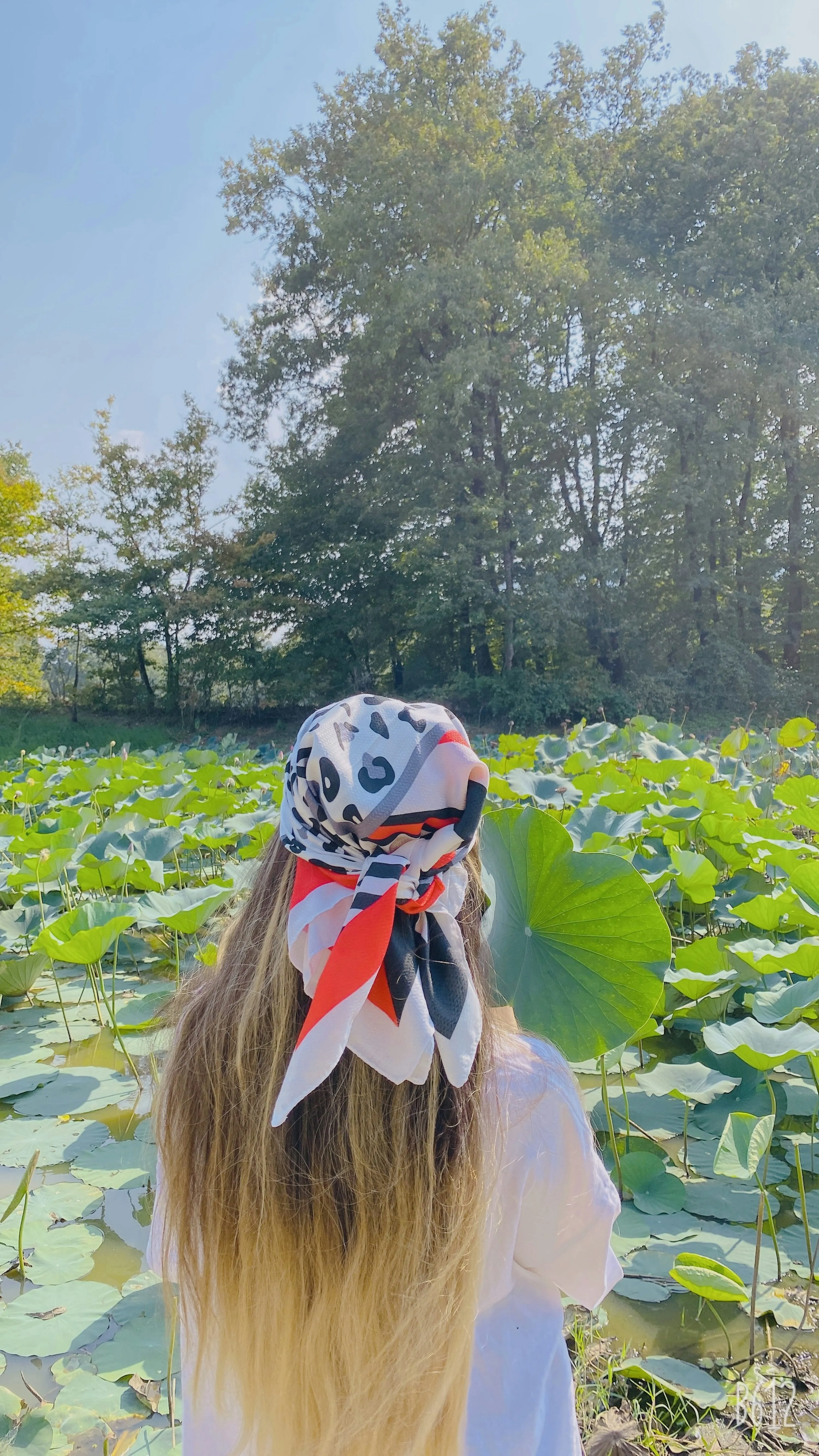 Young Girl with Long Hair Standing Near Green Plants