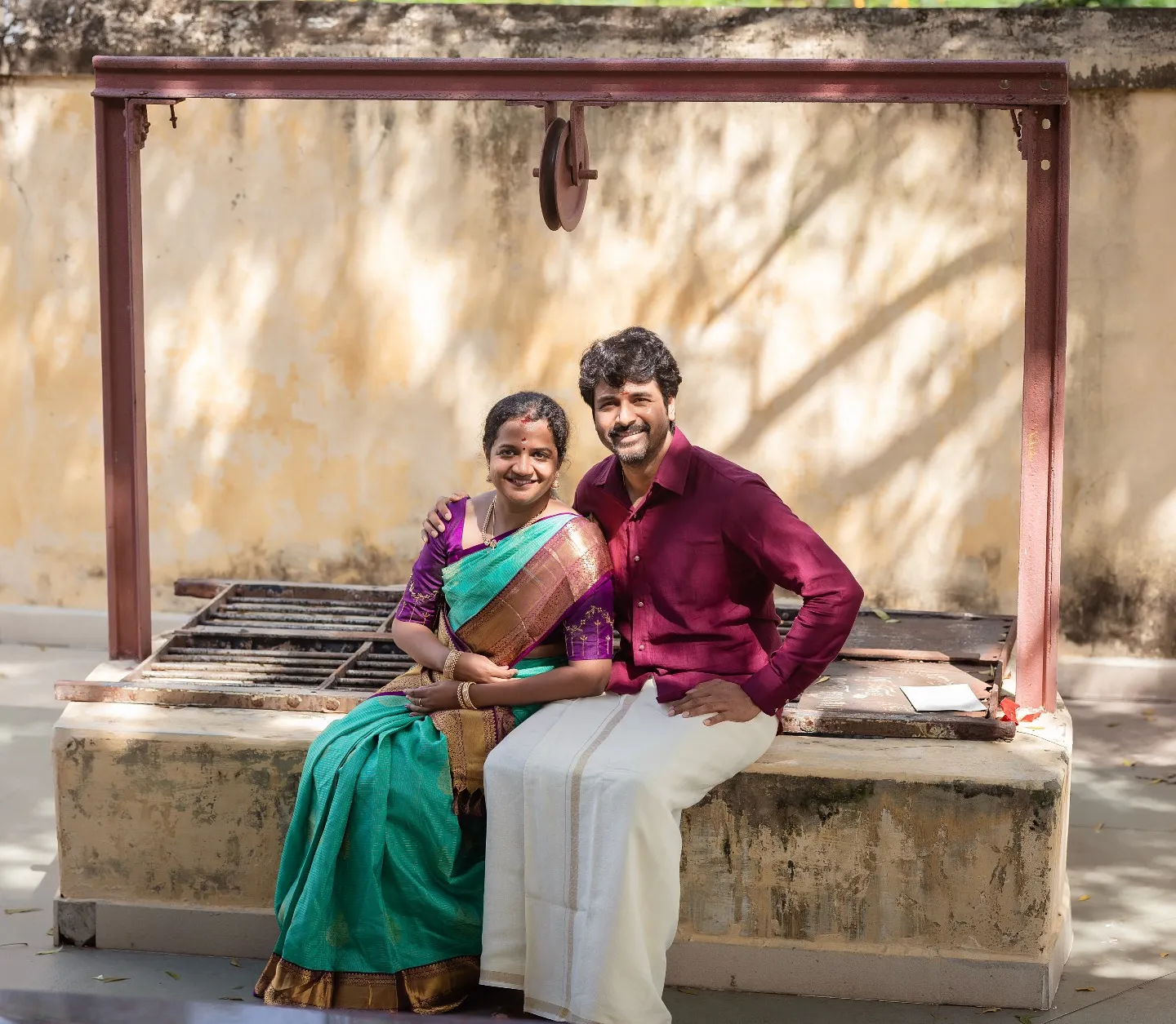 Sivakarthikeyan and His Wife Sitting on a Well Wallpaper