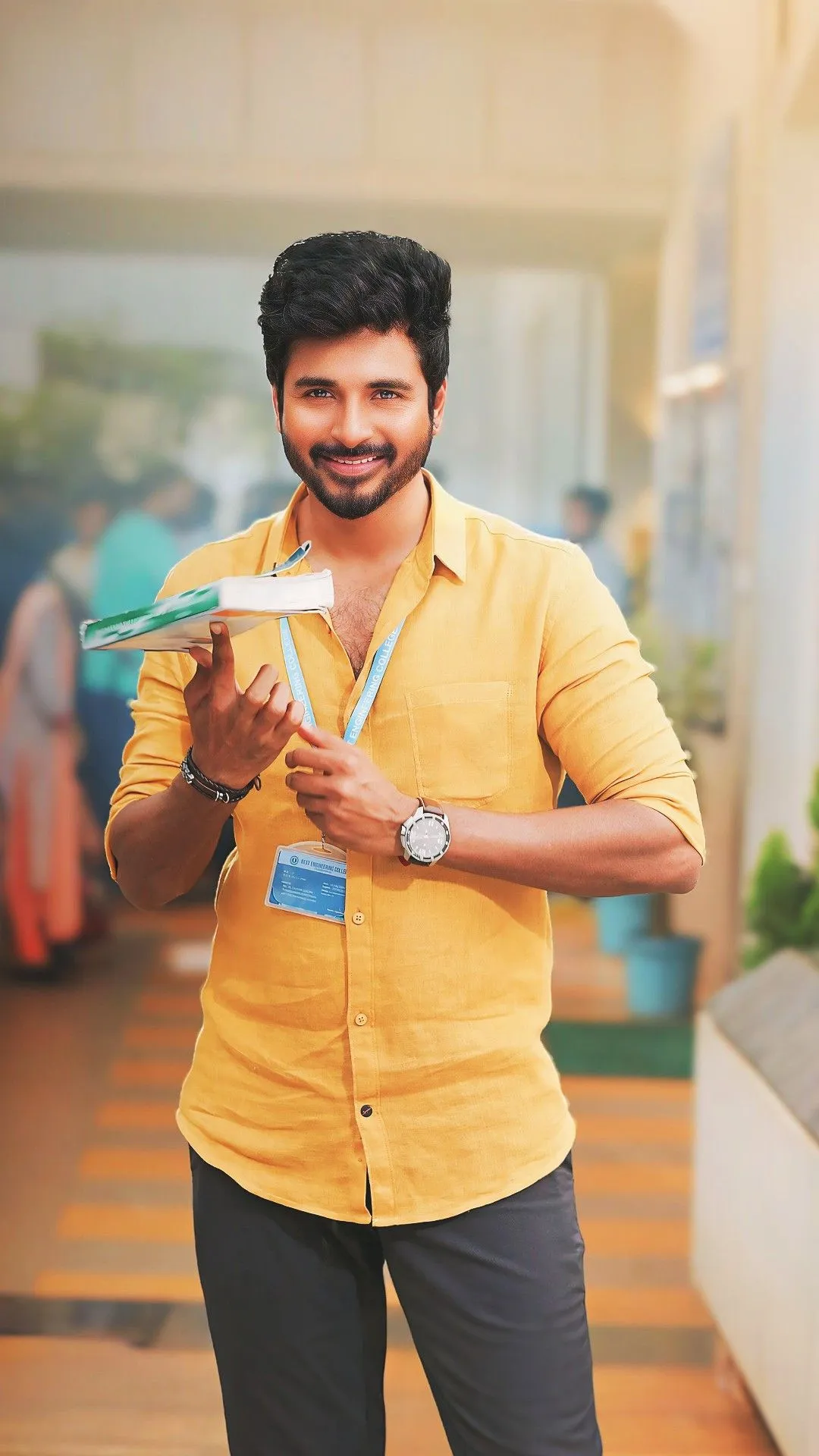Sivakarthikeyan Holding a Book Smiling in Yellow Shirt HD