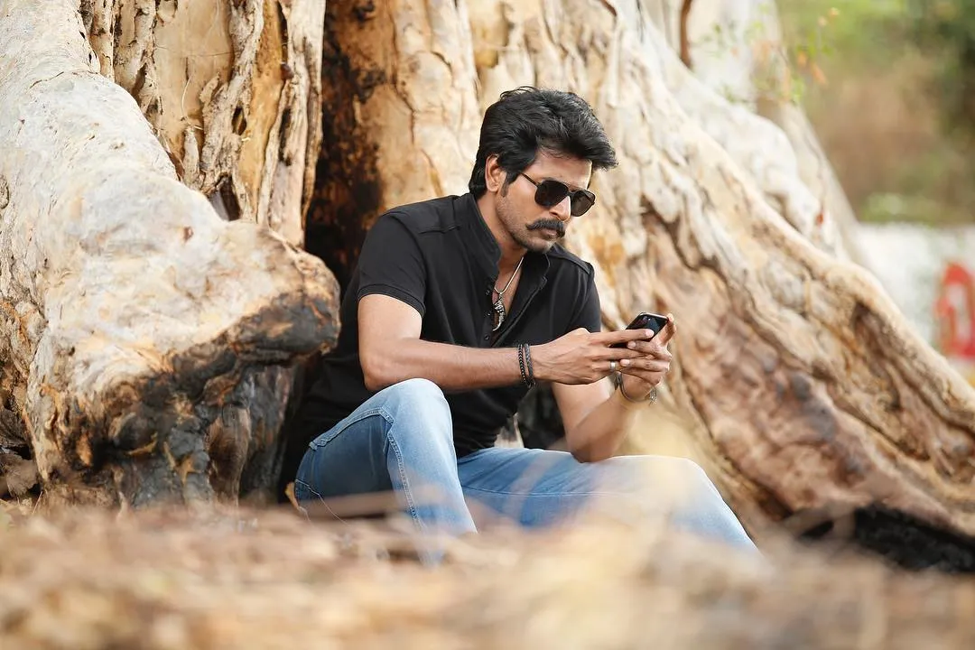 Sivakarthikeyan in a Black T Shirt Sitting Near a Tree Image