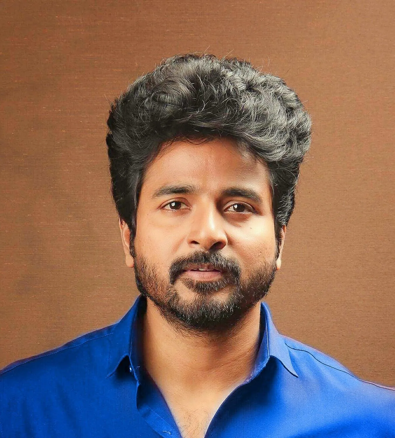 Sivakarthikeyan in Blue Shirt Looking with a Brown Backdrop