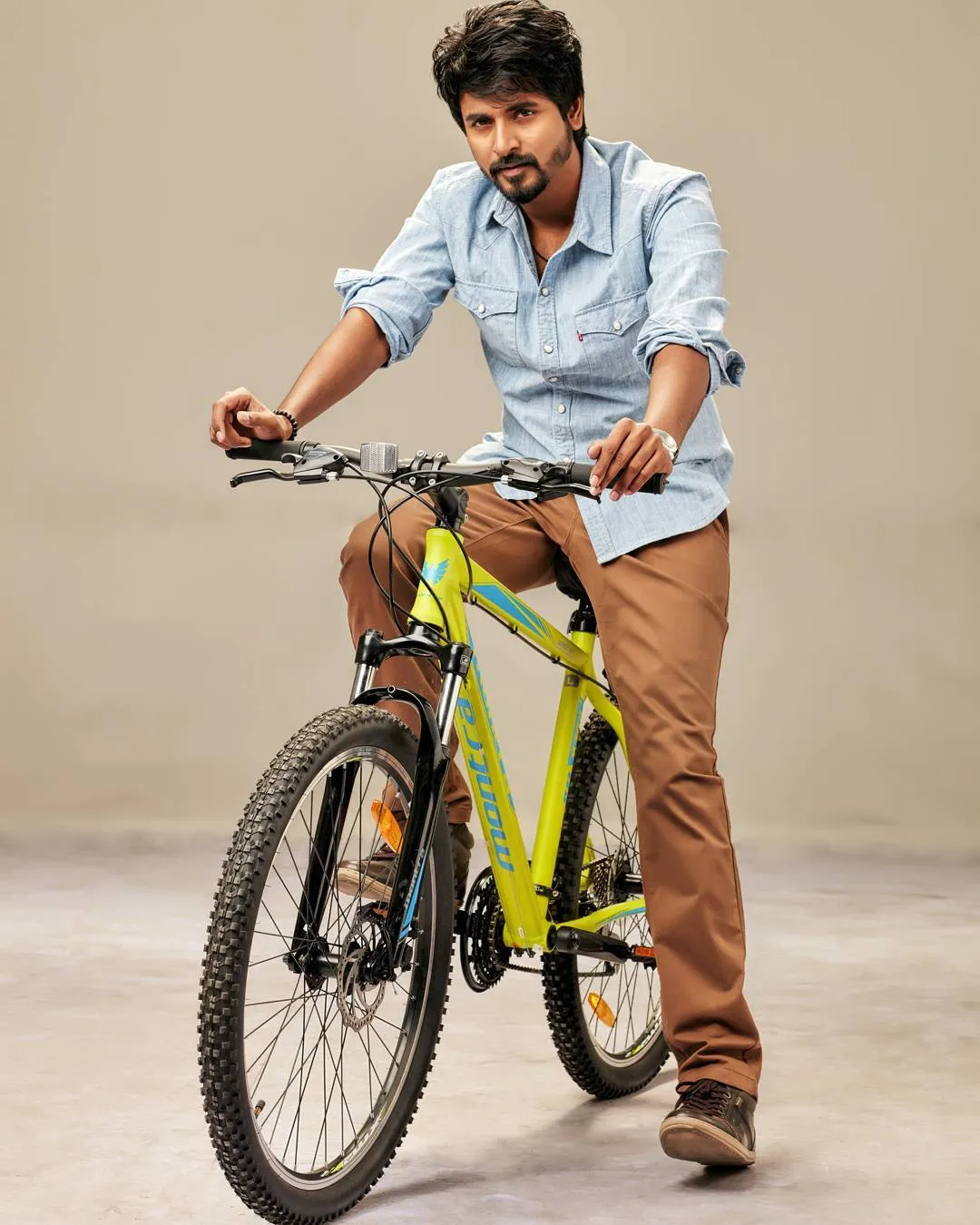 Sivakarthikeyan Sitting on a Cycle with Blue Shirt Image